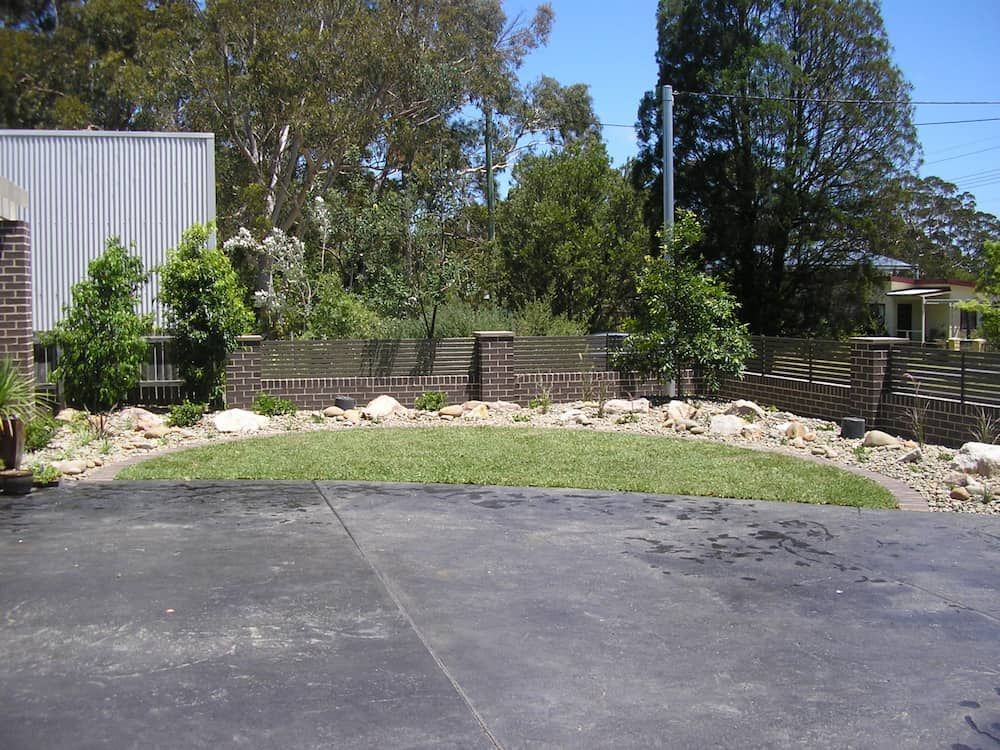 A Driveway With a Brick Wall and Trees — Peter Phillips Landscape Design in Bomaderry, NSW