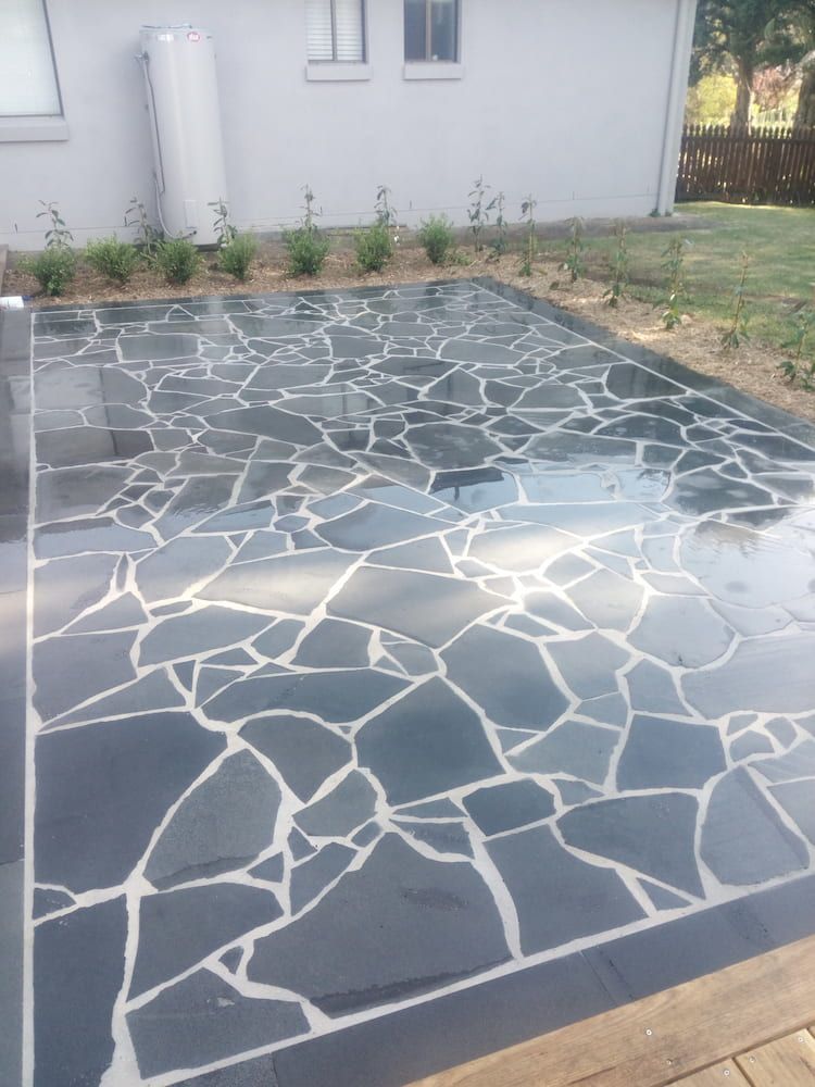 A Black and White Stone Patio in Front of a House — Peter Phillips Landscape Design in Bomaderry, NSW