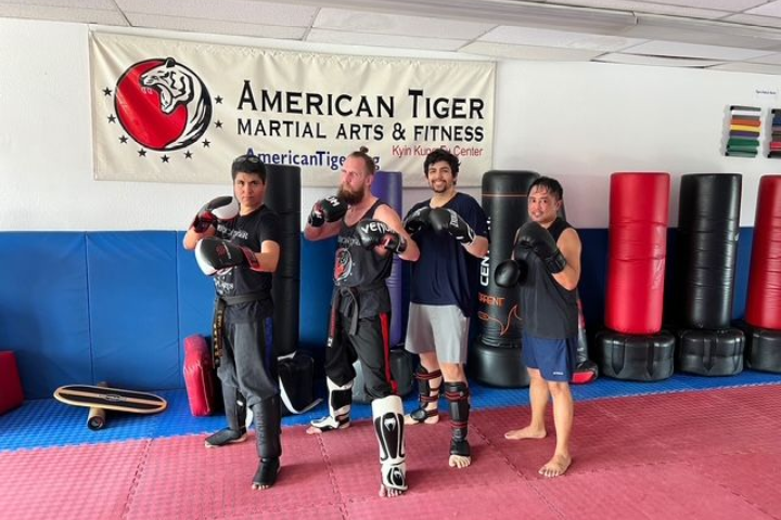 A group of people standing in front of a sign that says american tiger martial arts & fitness