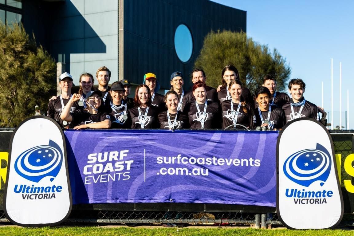 a group of people standing in front of a surf coast events banner .