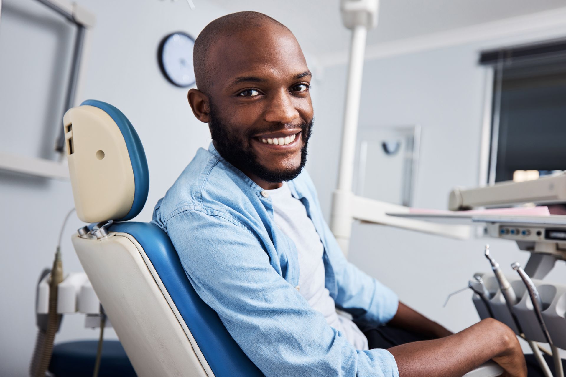 A man is sitting in a dental chair and smiling.