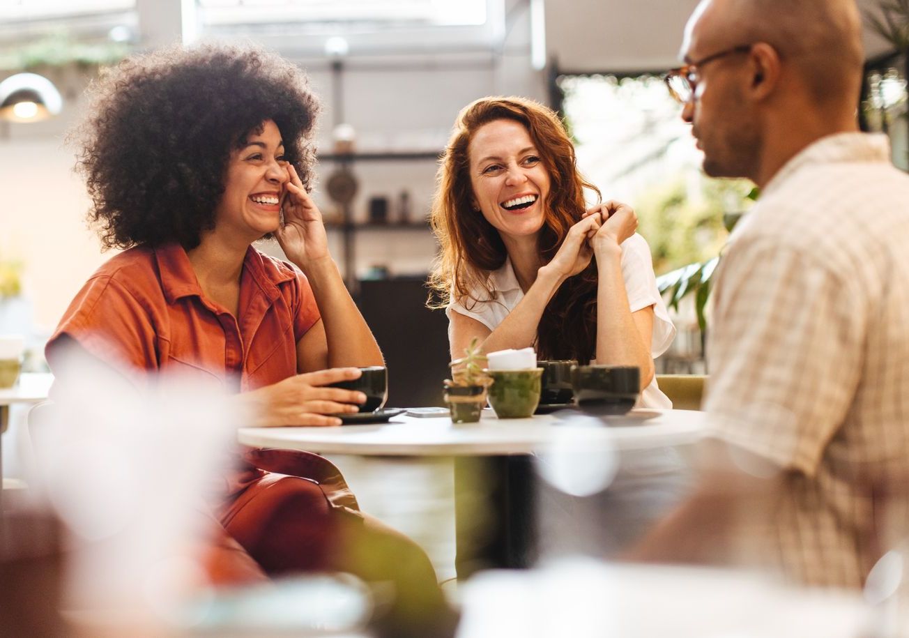 A group of people are sitting at a table in a restaurant drinking coffee.