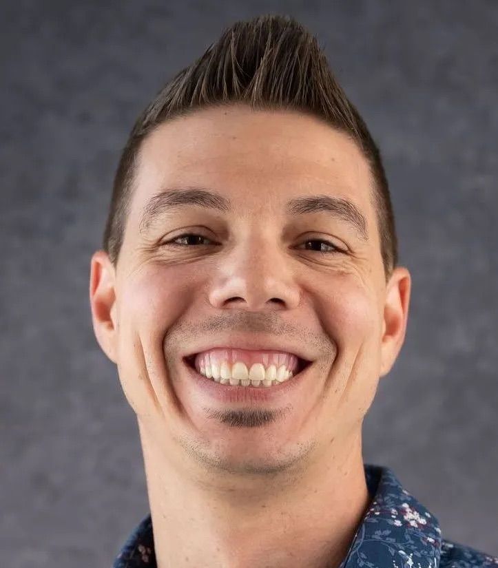 A man in a blue shirt is smiling for the camera.