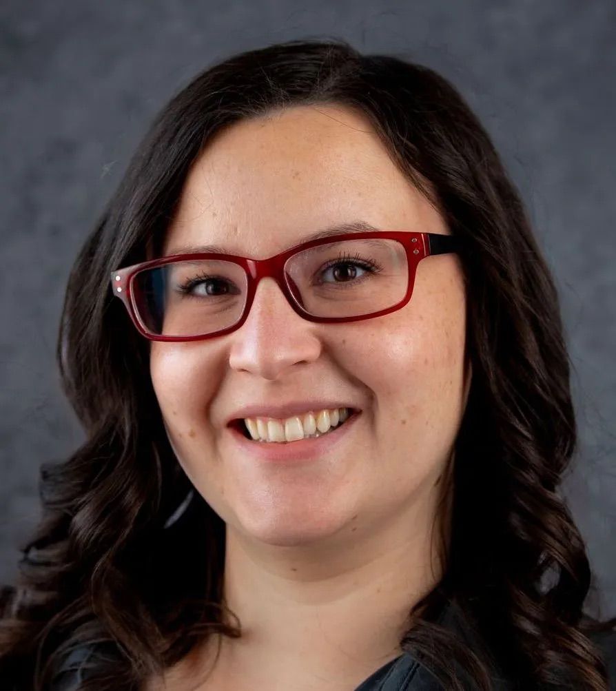 A woman wearing glasses is smiling for the camera.