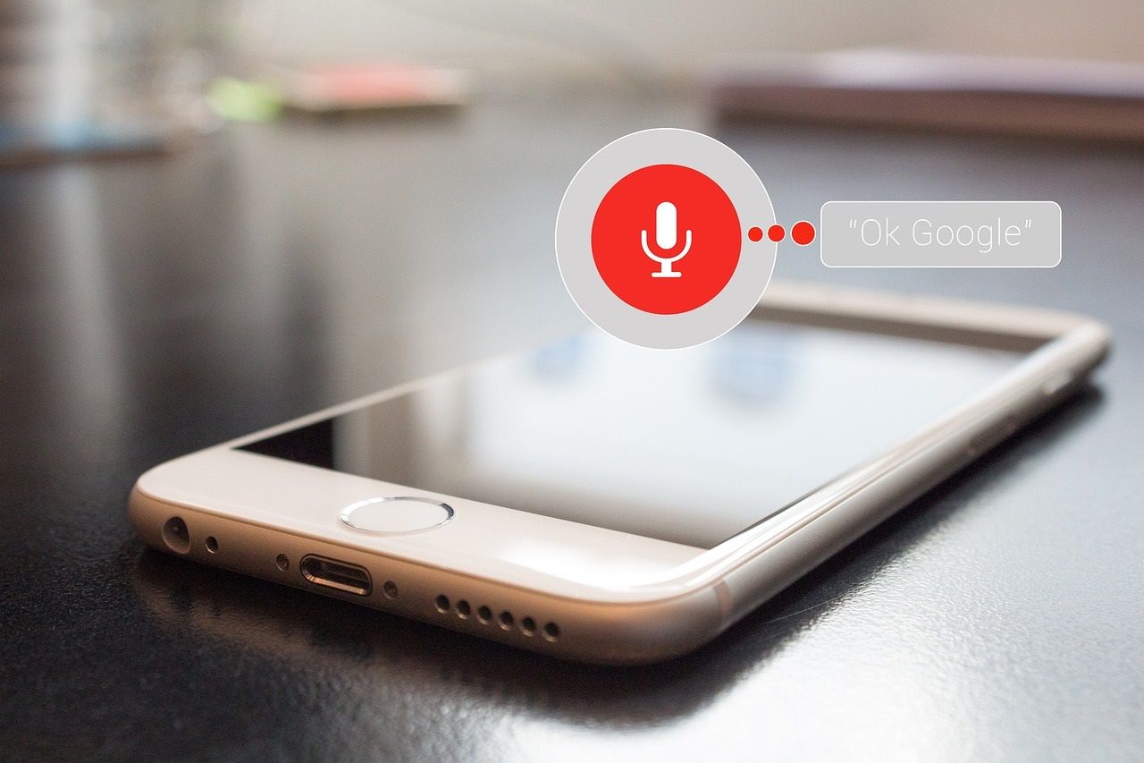 A smartphone on a table with a voice search icon on it.