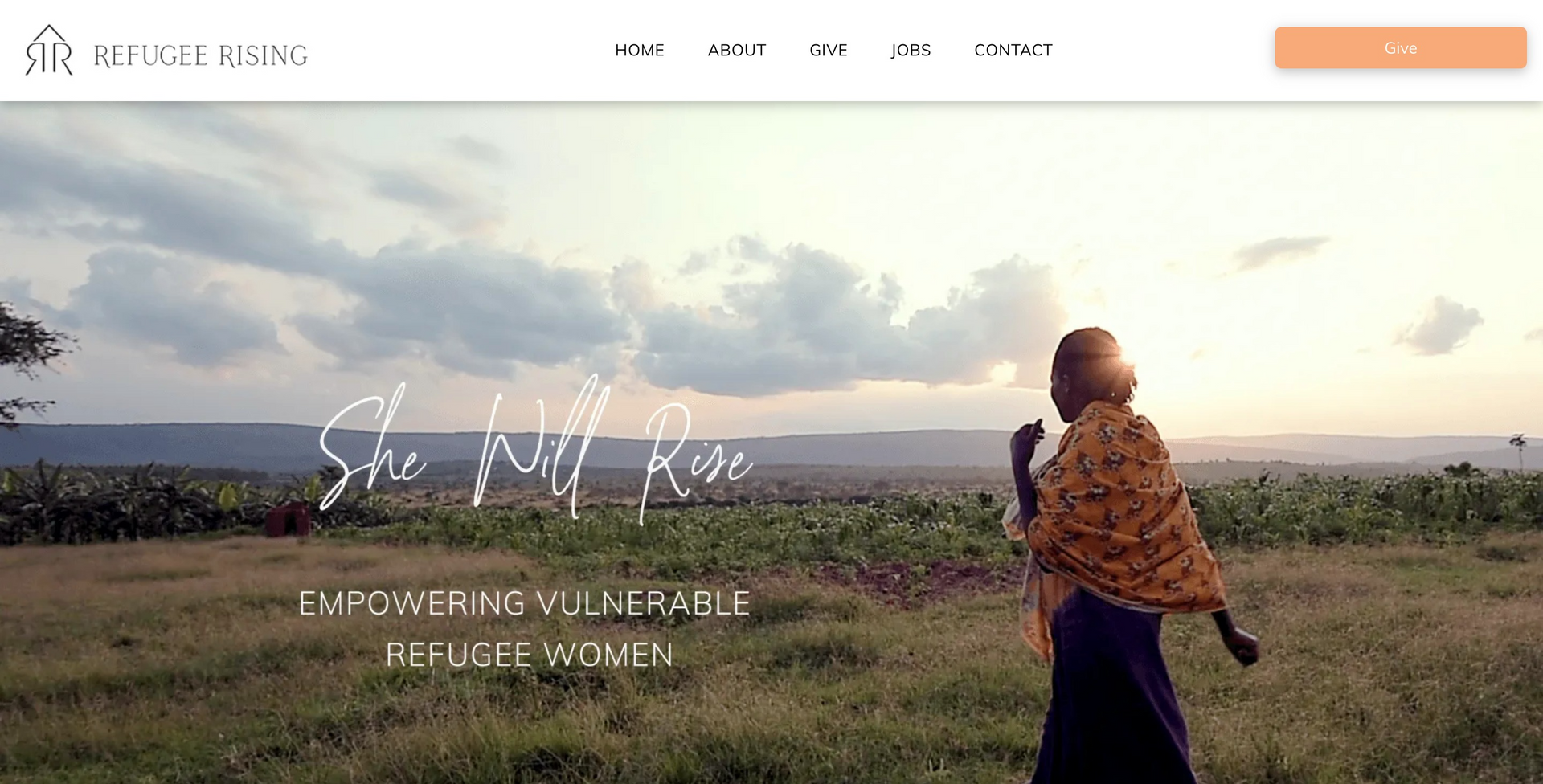 A woman in a scarf is standing in a field.