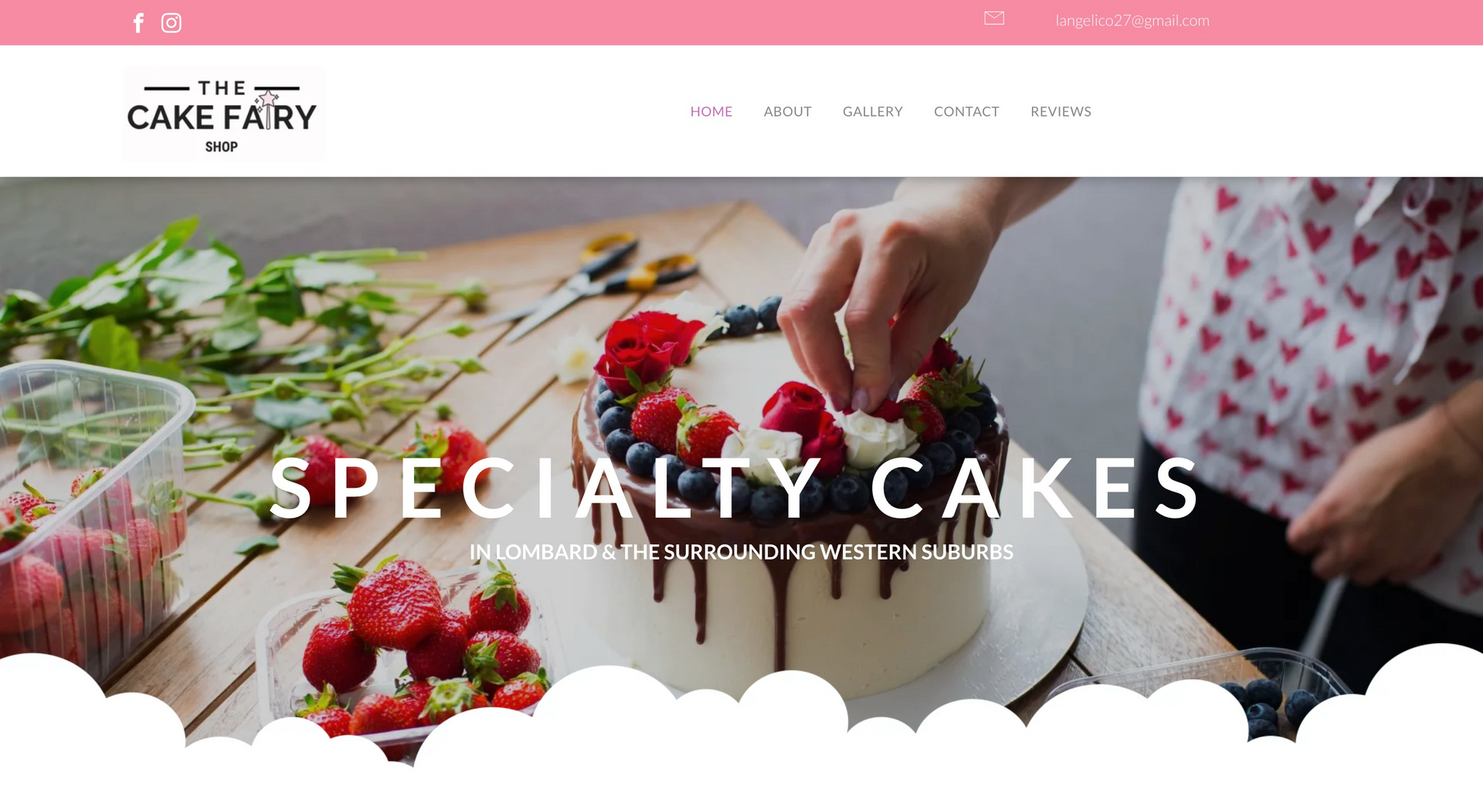 A woman is decorating a cake with strawberries and blueberries on a wooden table.
