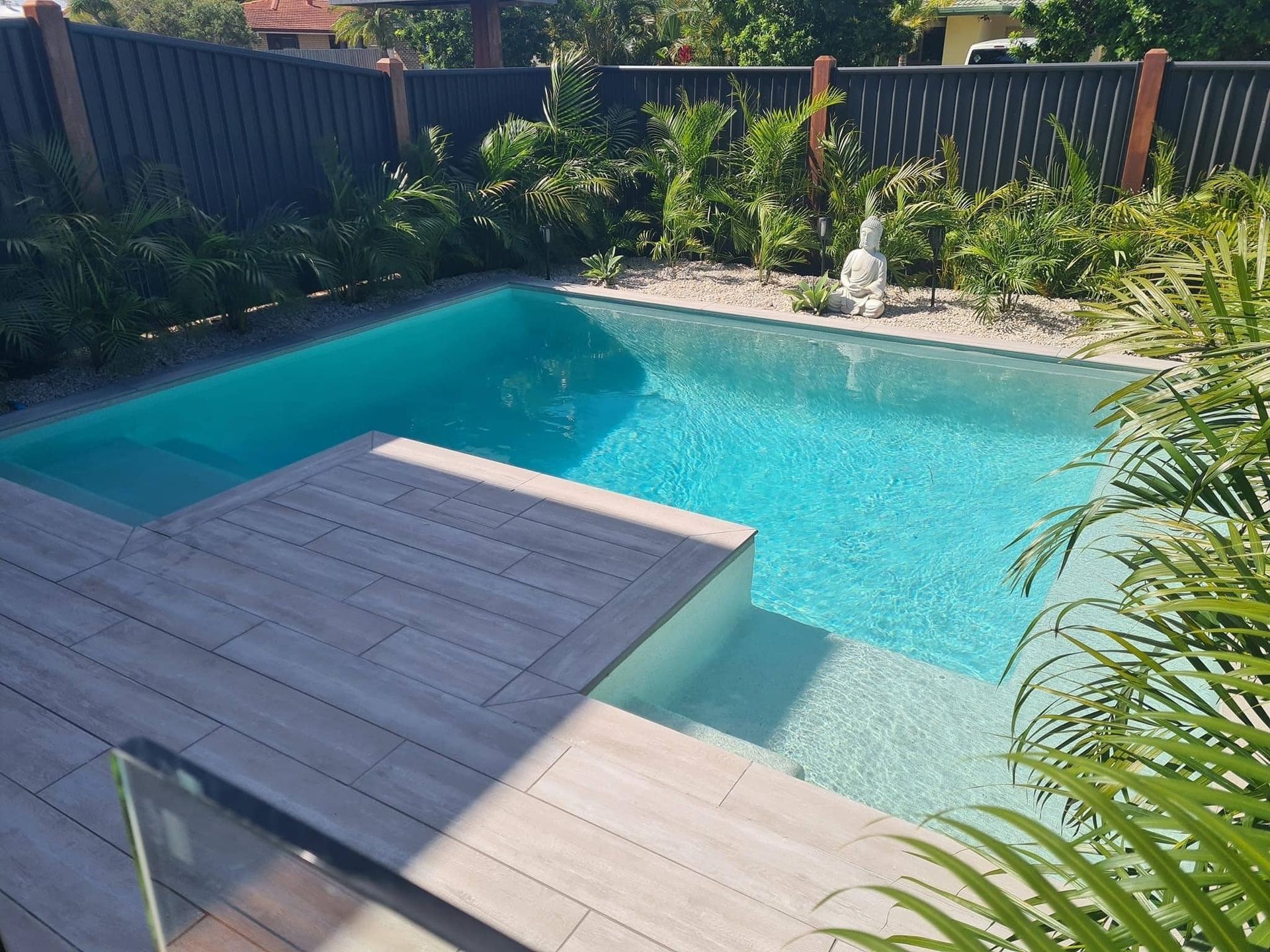 Swimming pool with light blue water and wooden deck — Mad Pool Interiors and Renovations in Baringa, QLD
