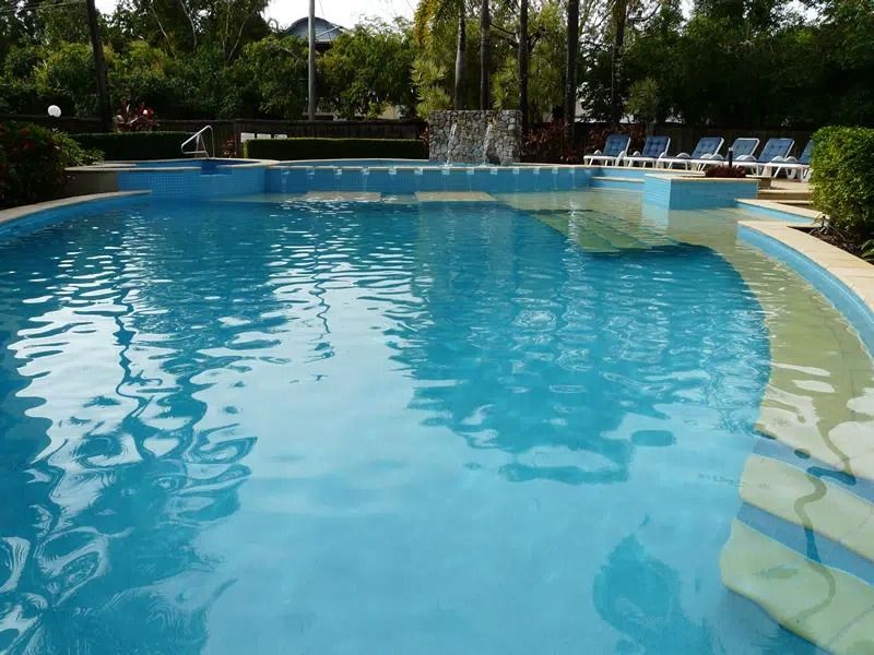 Blue Outdoor Swimming Pool With Lounge Chairs and Trees — Mad Pool Interiors and Renovations in Baringa, QLD
