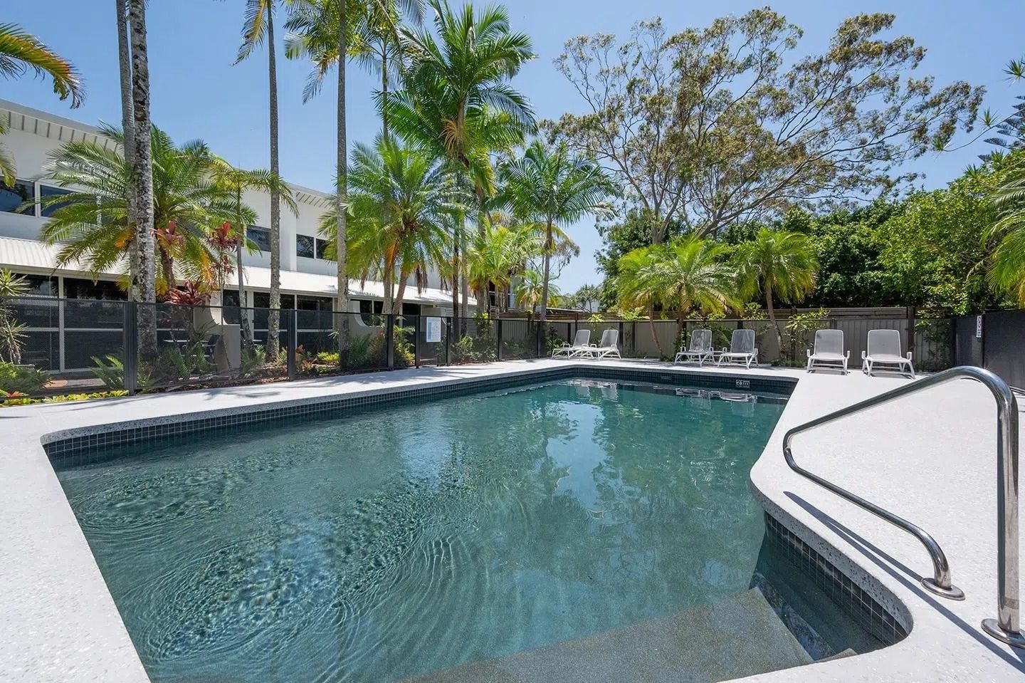 Outdoor Swimming Pool With Blue Water Beside a Modern Building — Mad Pool Interiors and Renovations in Baringa, QLD