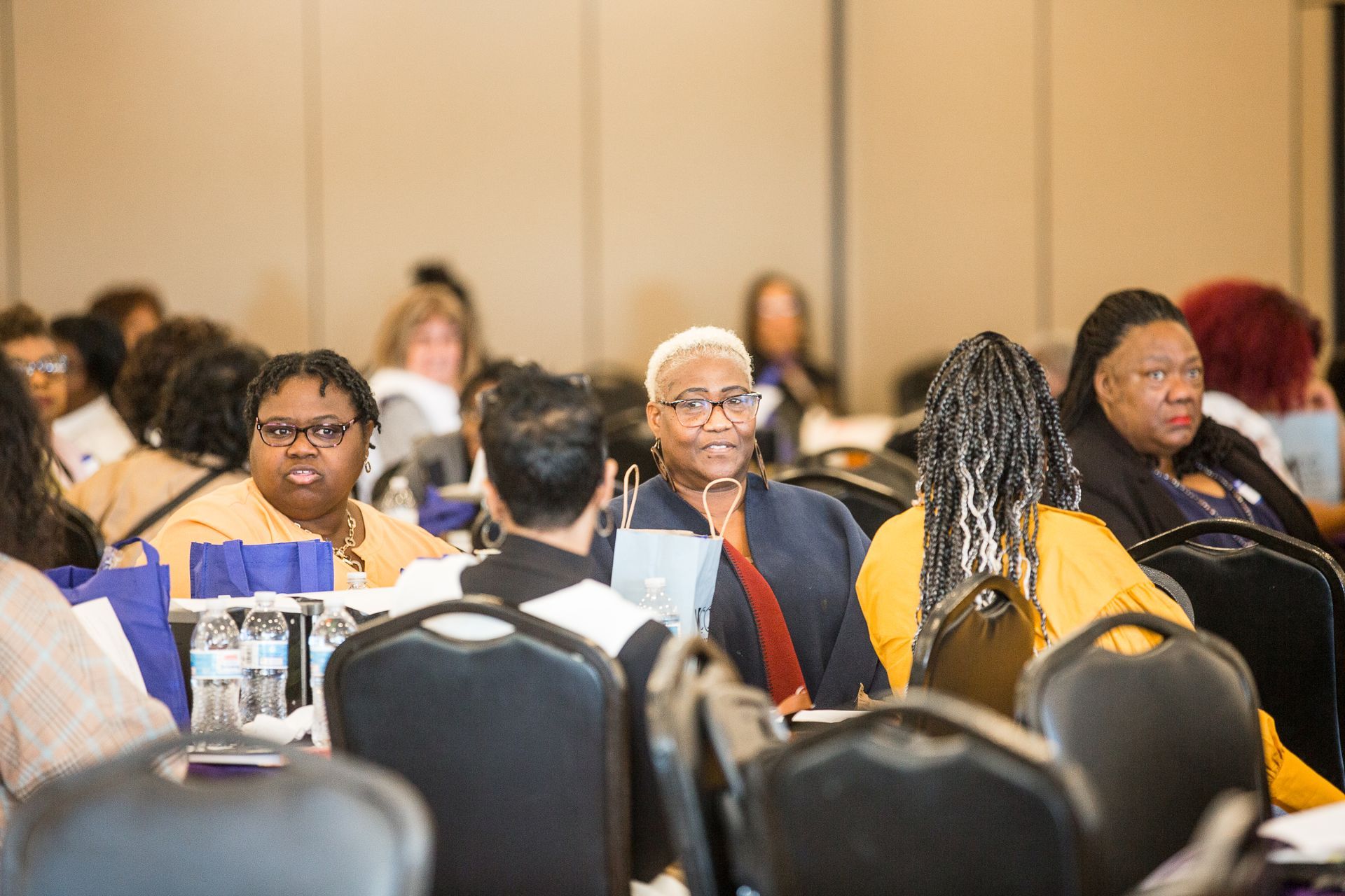 A group of people are sitting at tables in a conference room.