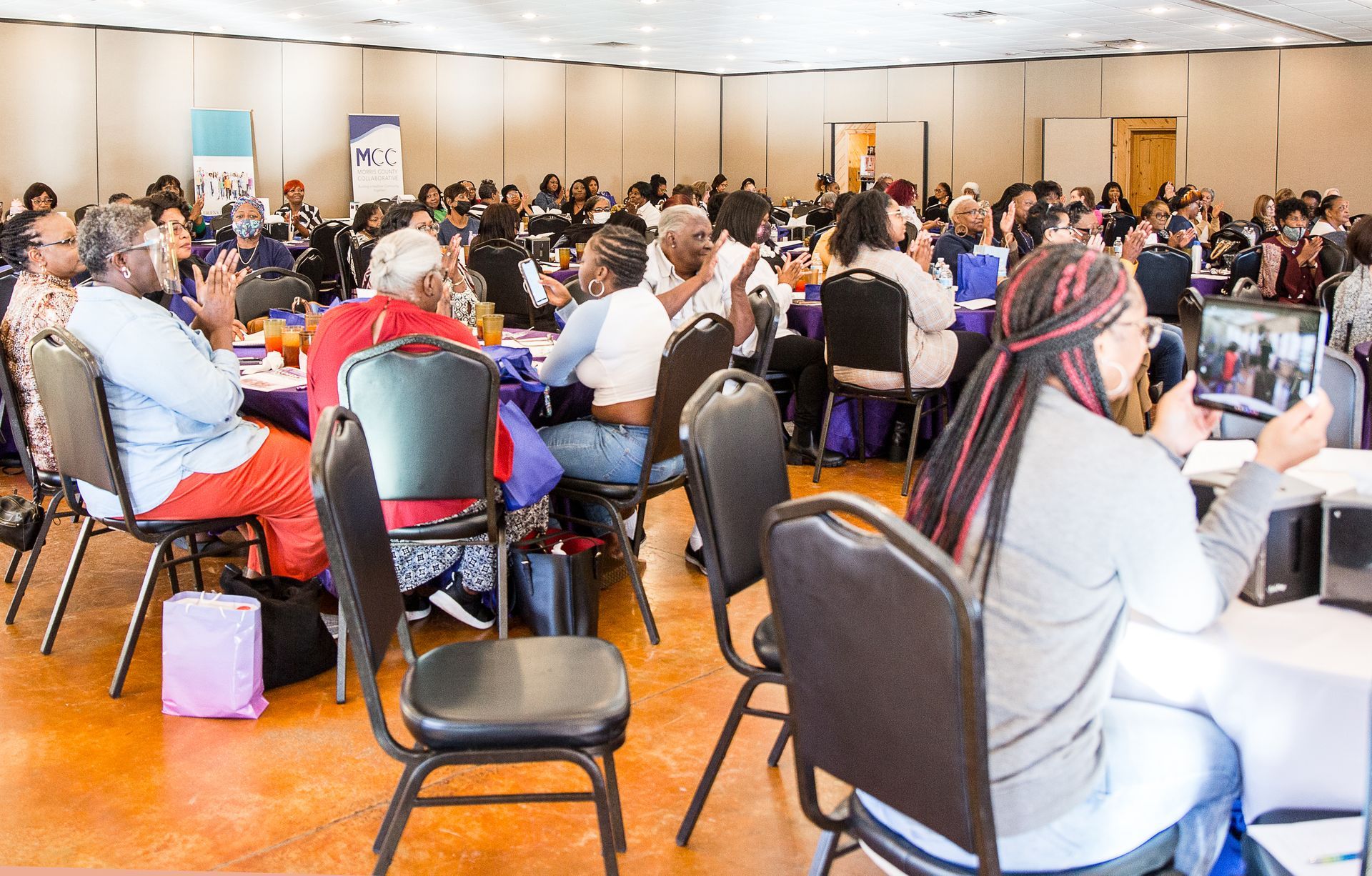 A large group of people are sitting at tables in a conference room.