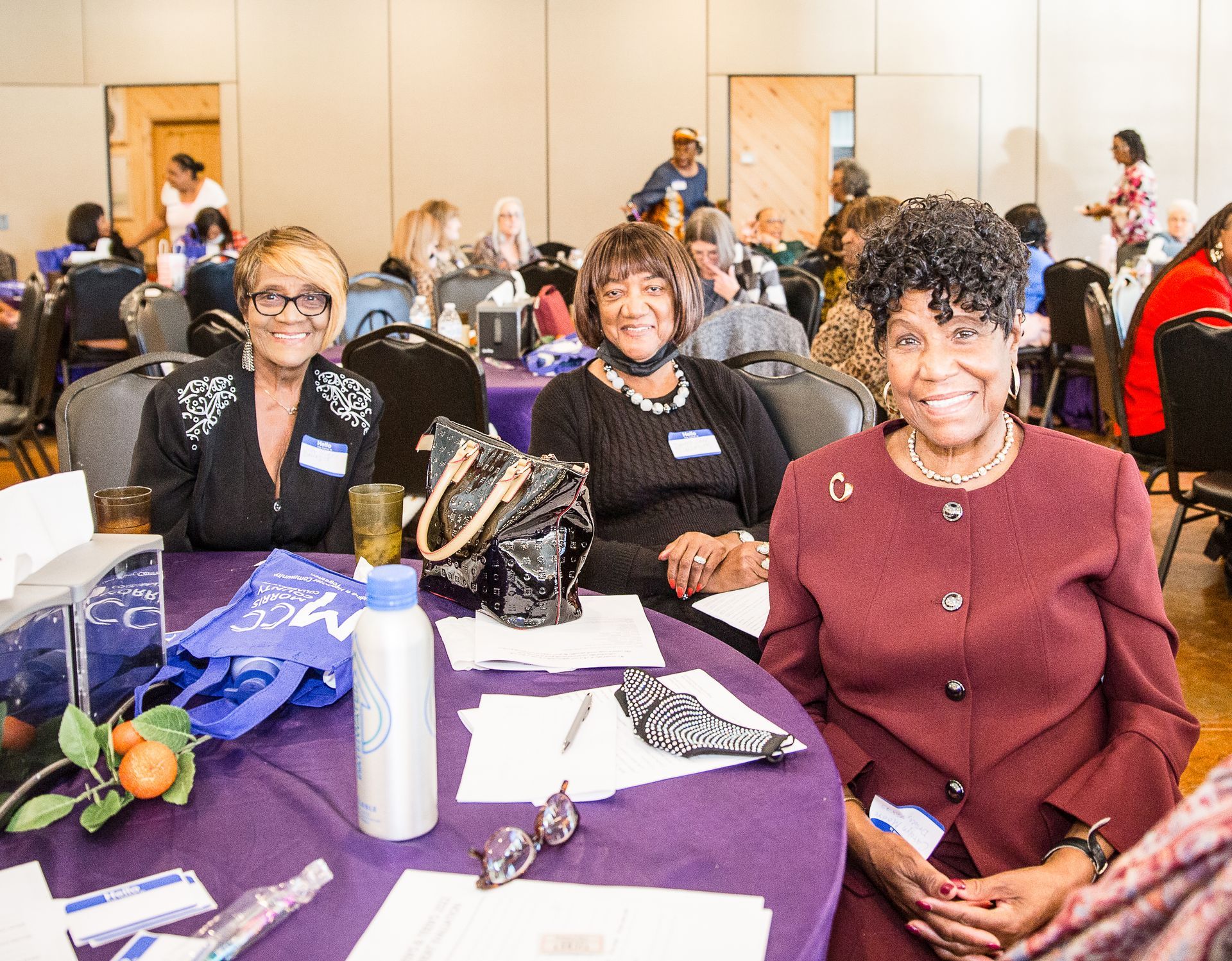 Three women are sitting at a table at a conference.