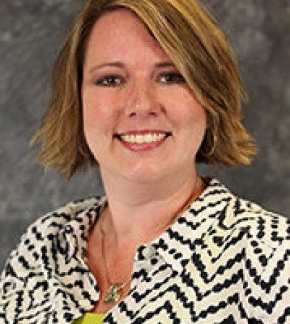 A woman wearing a black and white striped jacket is smiling for the camera.