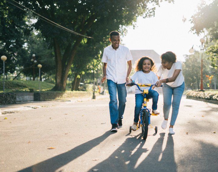 parents teaching their child how to drive a bike