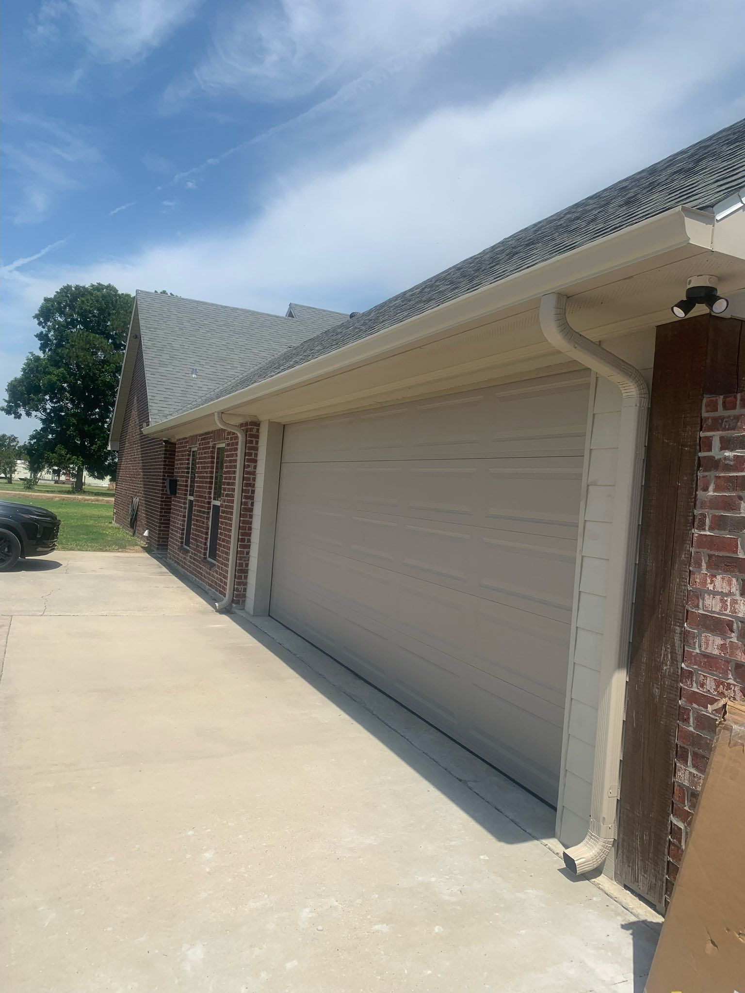 Brick house with a beige garage door and a concrete driveway under a blue sky