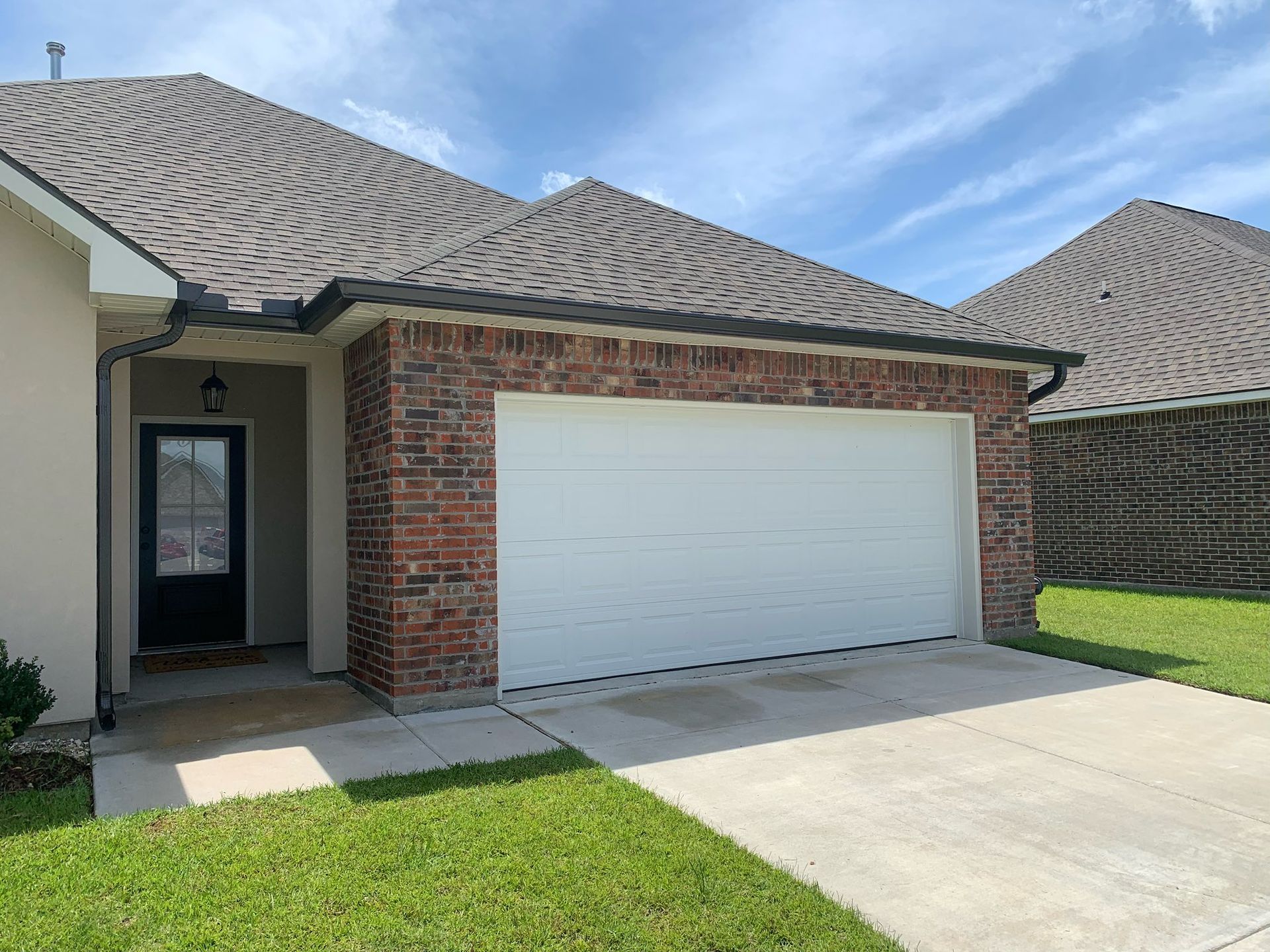 Brick single-story house exterior with a two-car garage and concrete driveway