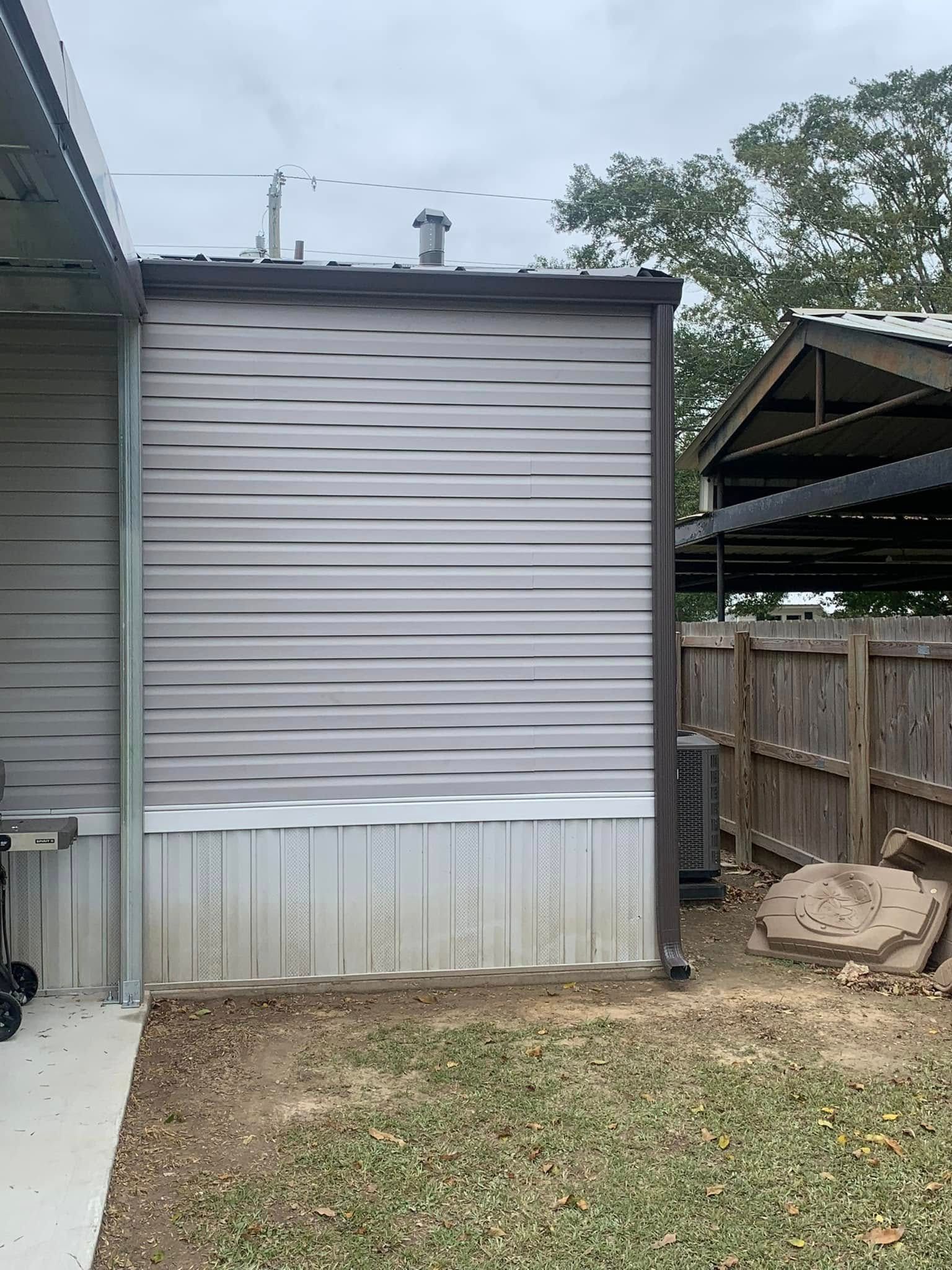 A mobile home with a shed and a fence in the backyard.