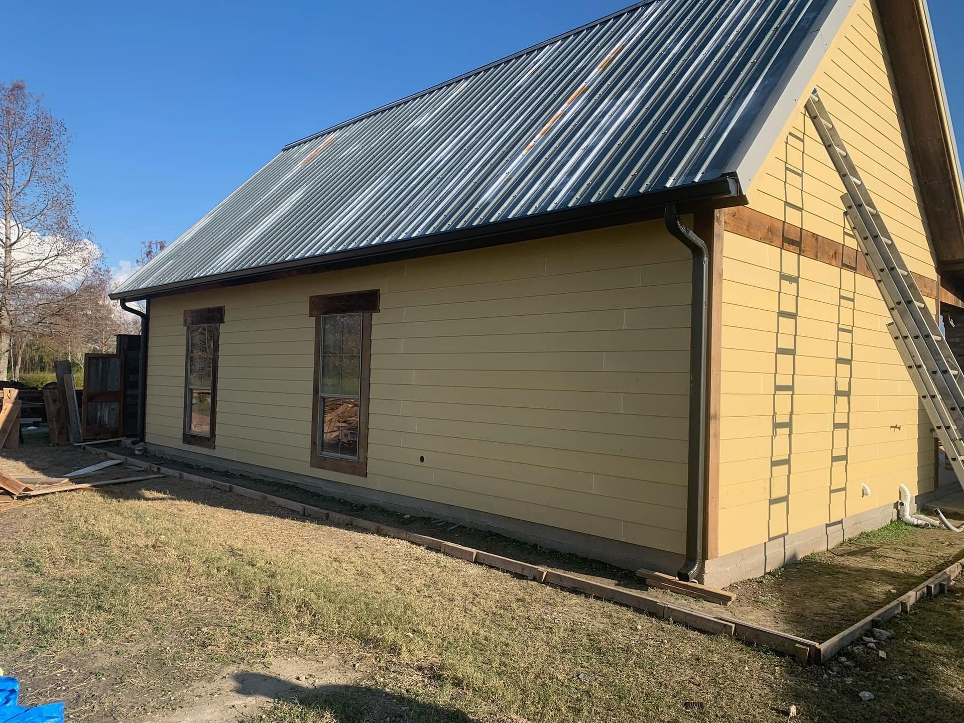 A yellow house with a metal roof is being built.