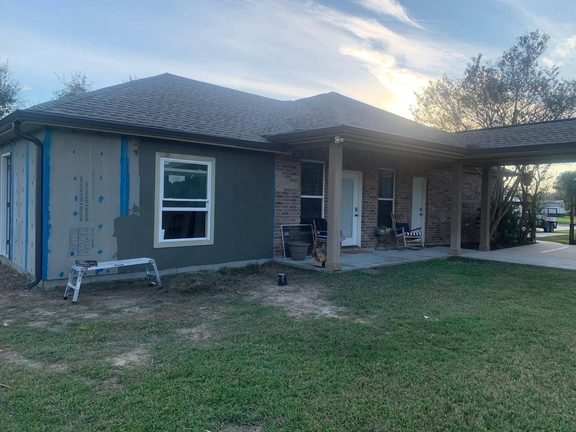 A house is being painted in a gray color and has a porch.