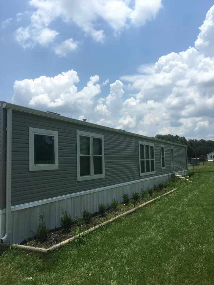 A mobile home is sitting on top of a lush green field.