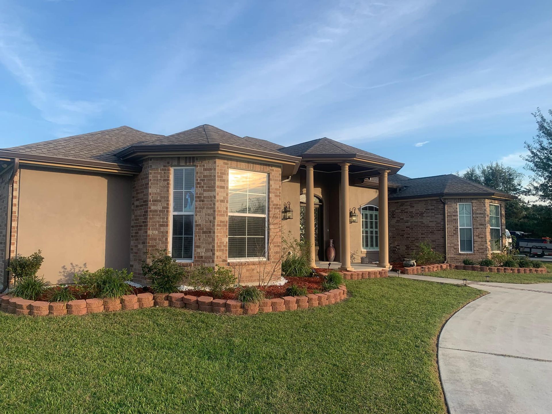 A large brick house with a lush green lawn in front of it.
