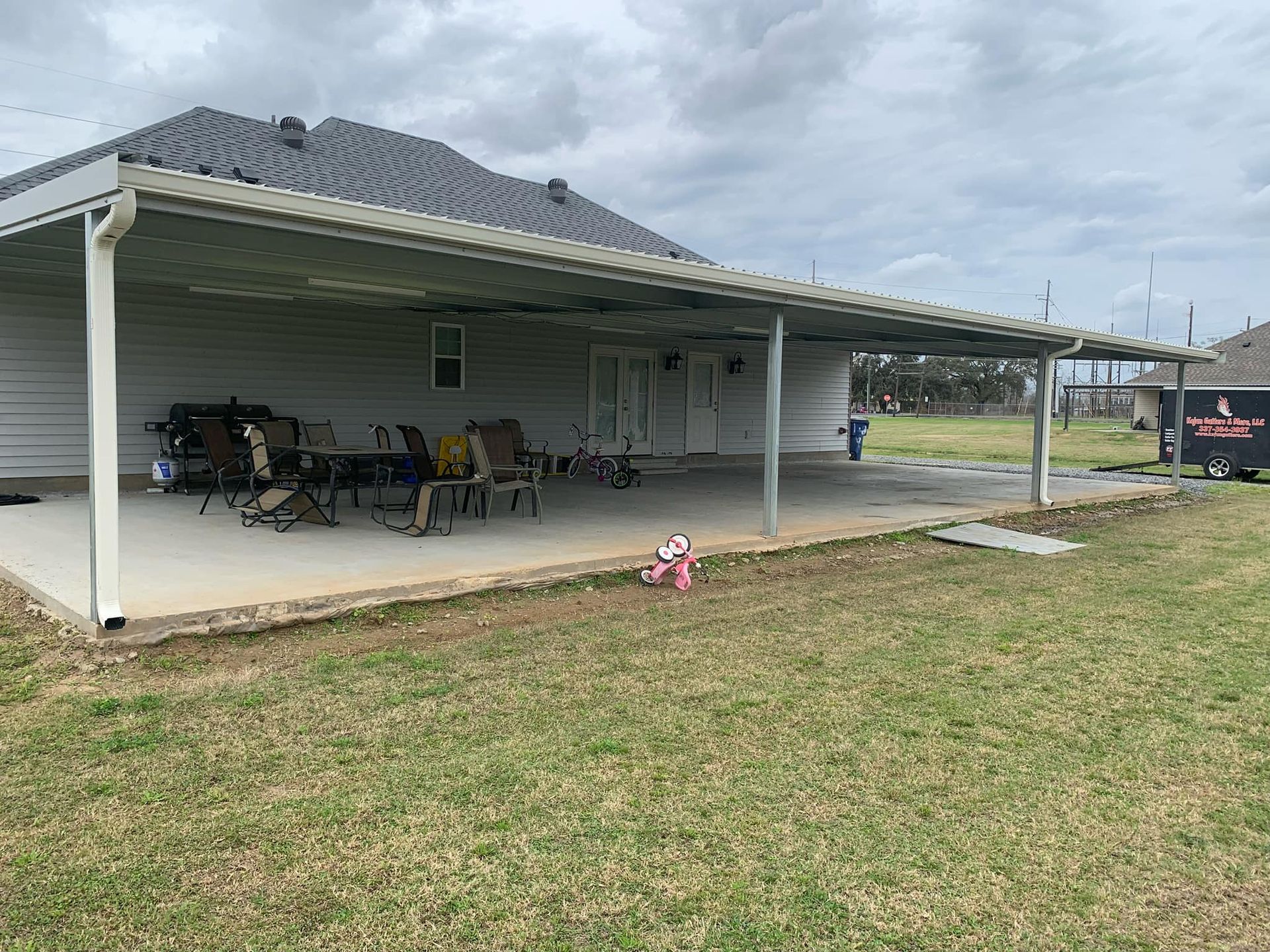 There is a large covered patio area in front of a house.