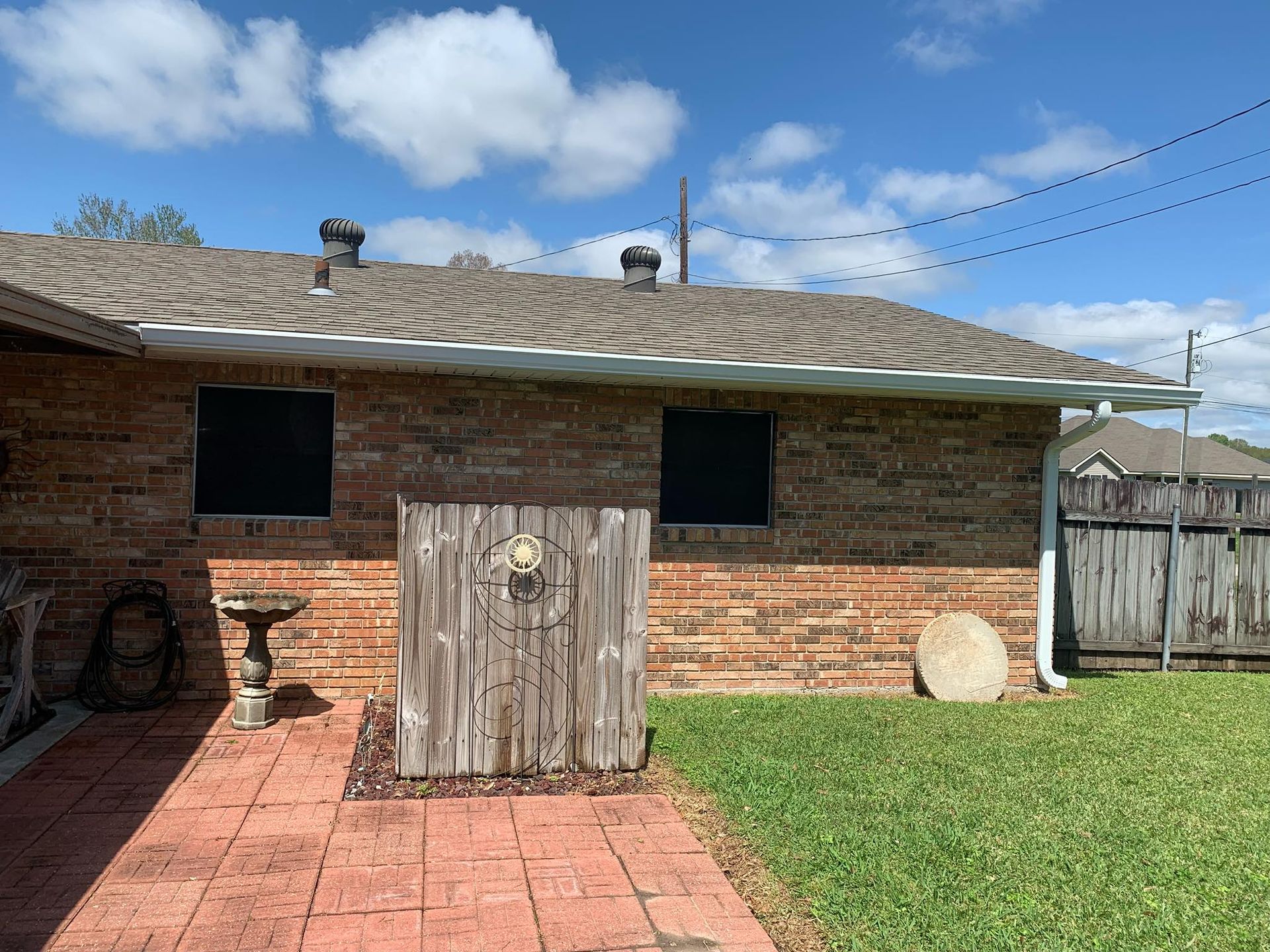 A brick house with a wooden fence in the backyard.
