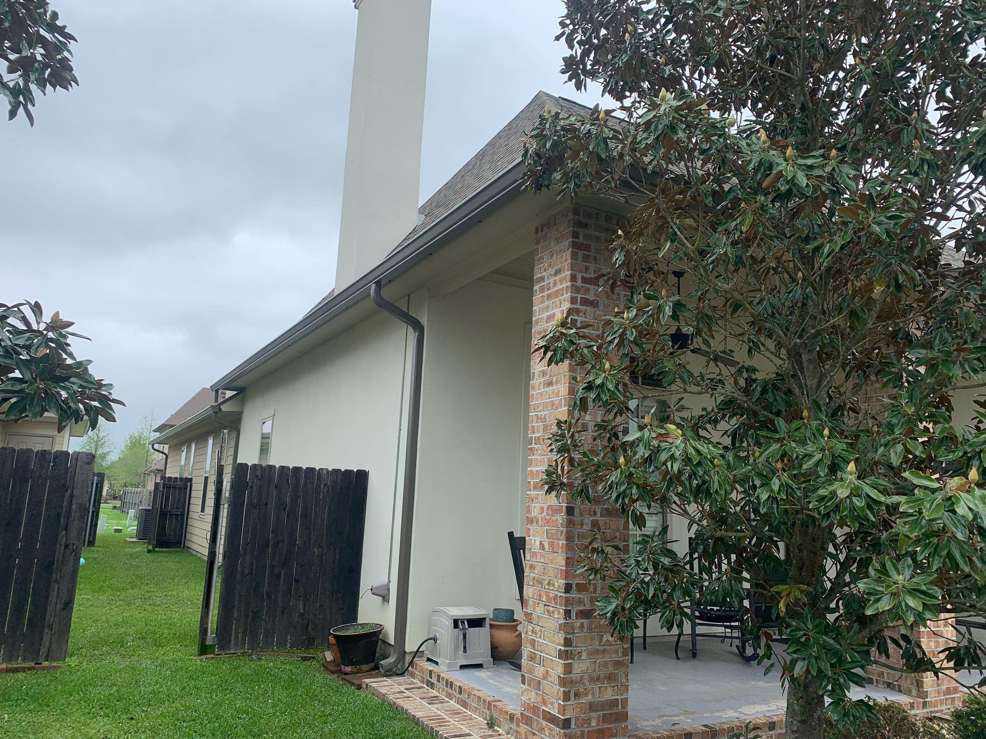 A house with a chimney on the side of it and a tree in front of it.