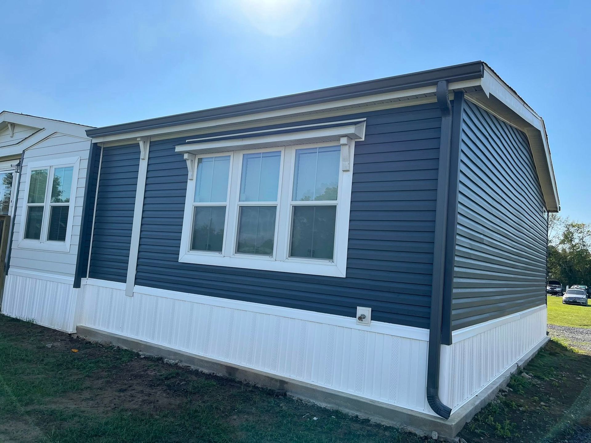 Blue and white mobile home exterior with windows and vinyl siding