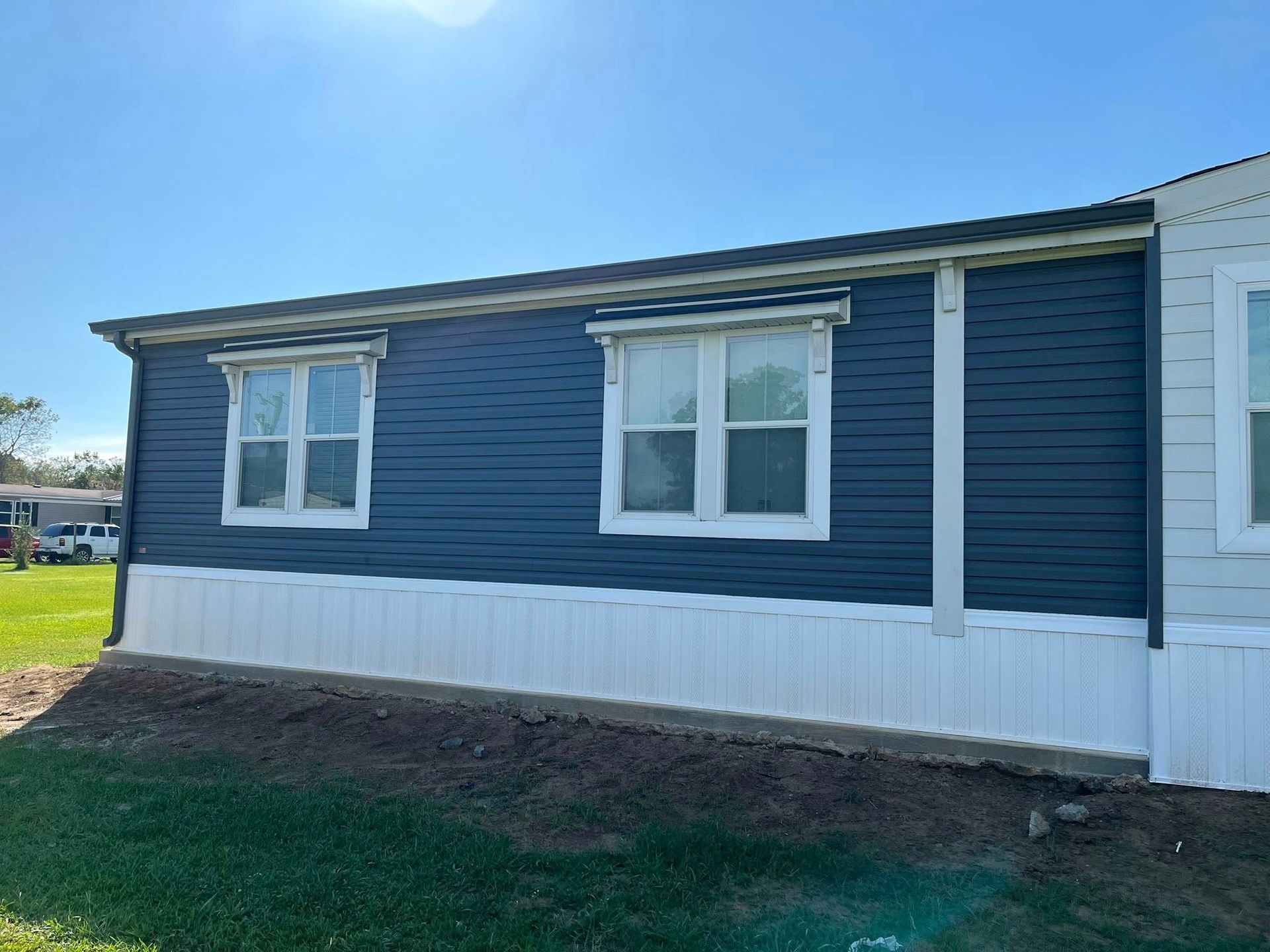 Blue house exterior with white trim and two windows on a sunny day