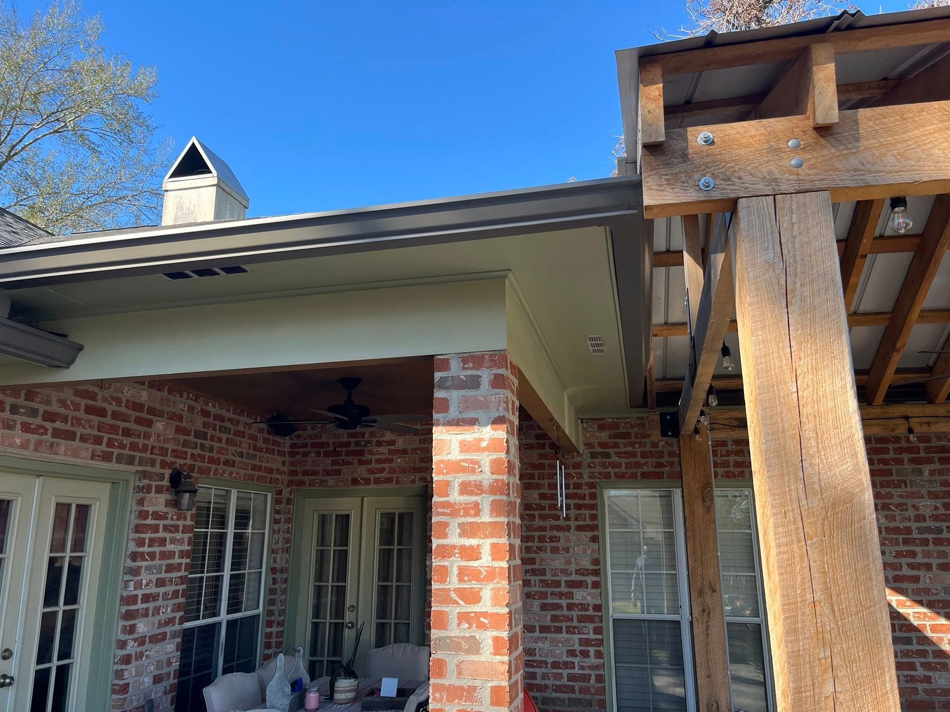Brick house porch with white trim and a large wooden support post under a blue sky