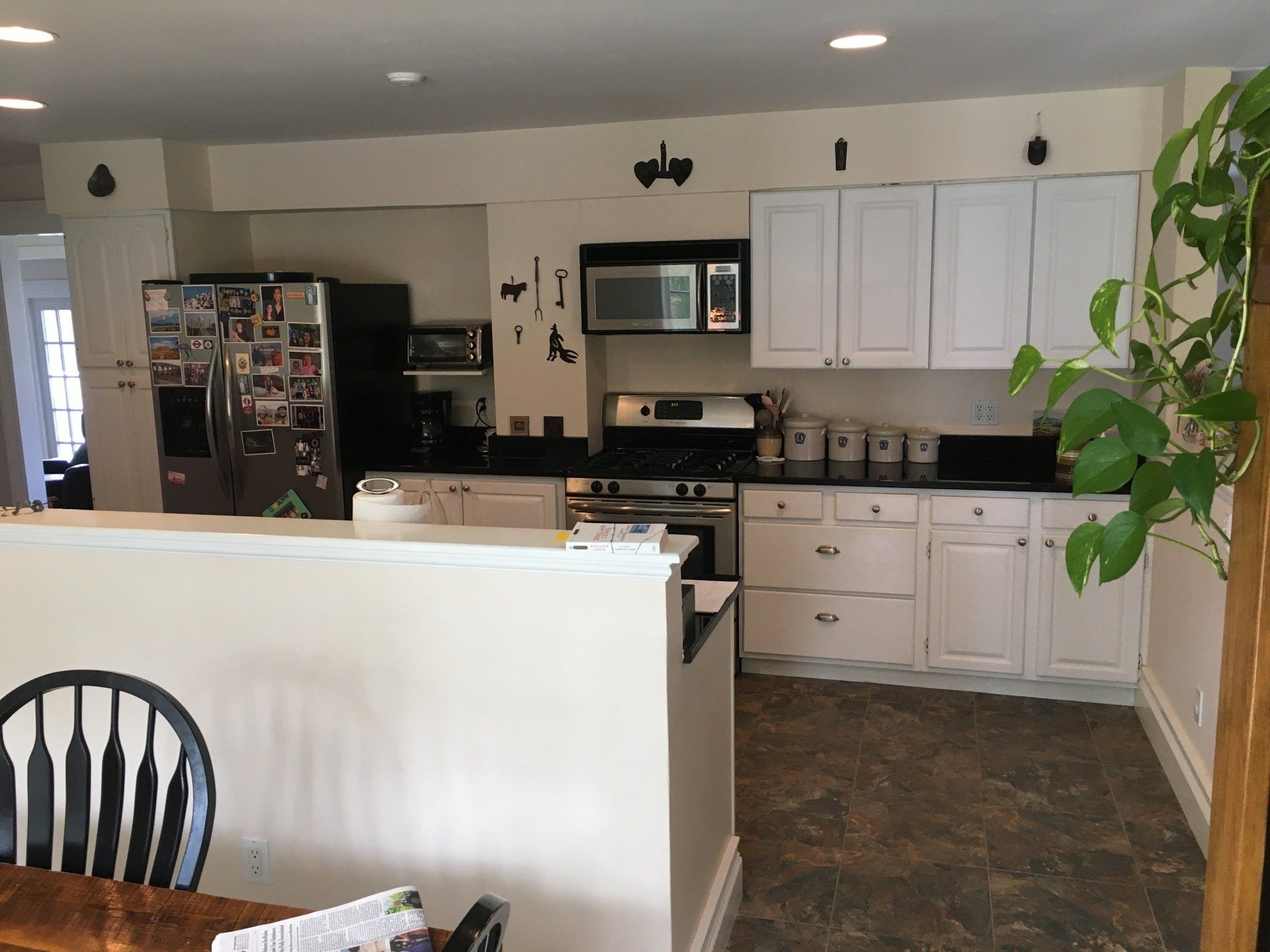 Modern kitchen and dining area with white cabinets, black countertops, and a refrigerator.