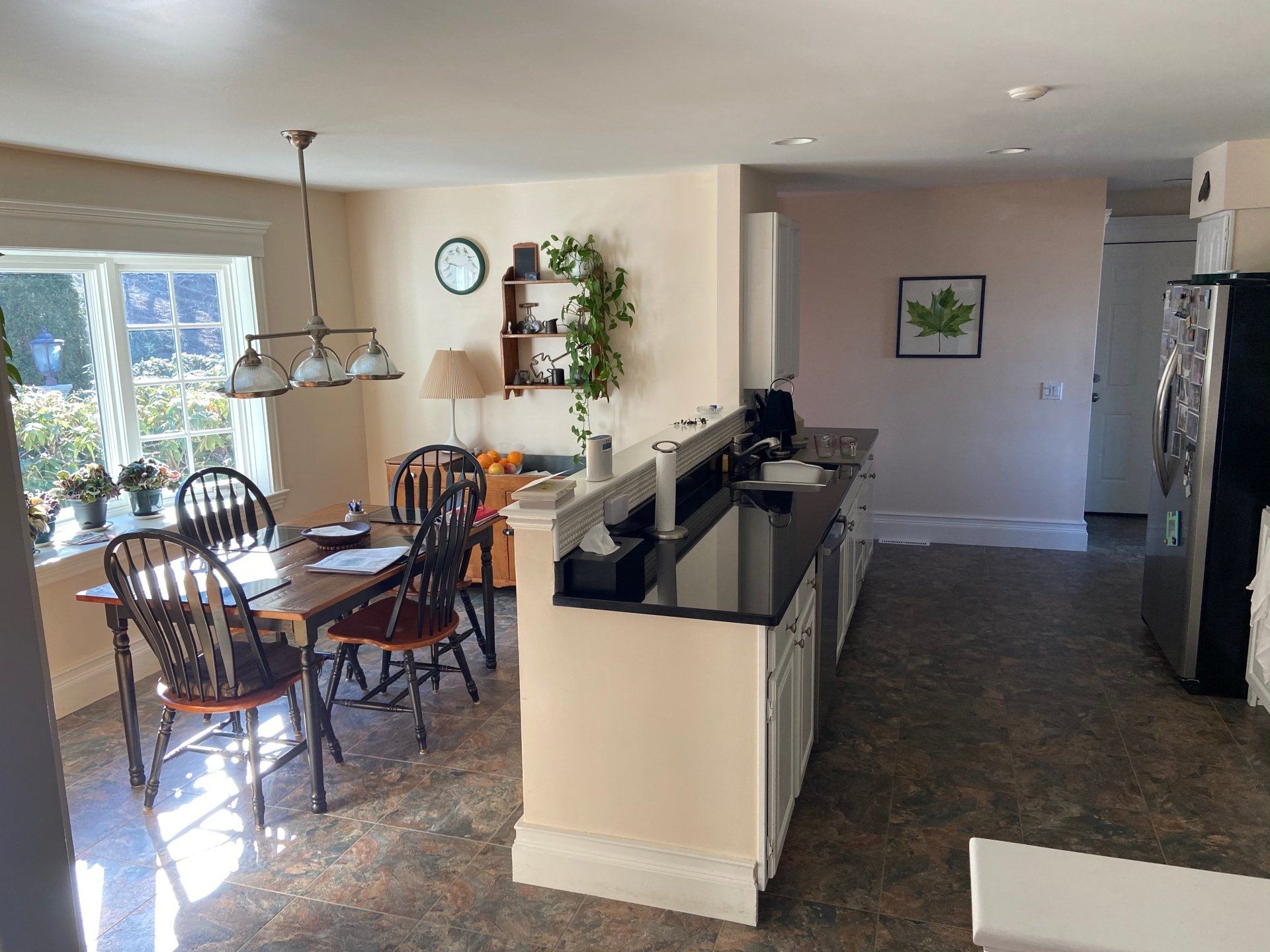 Open kitchen and dining area with dark cabinets, wood table, and large windows.
