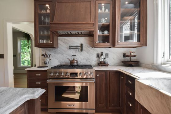 Bright modern kitchen with island, white cabinets, dark countertops, and large window over sink.