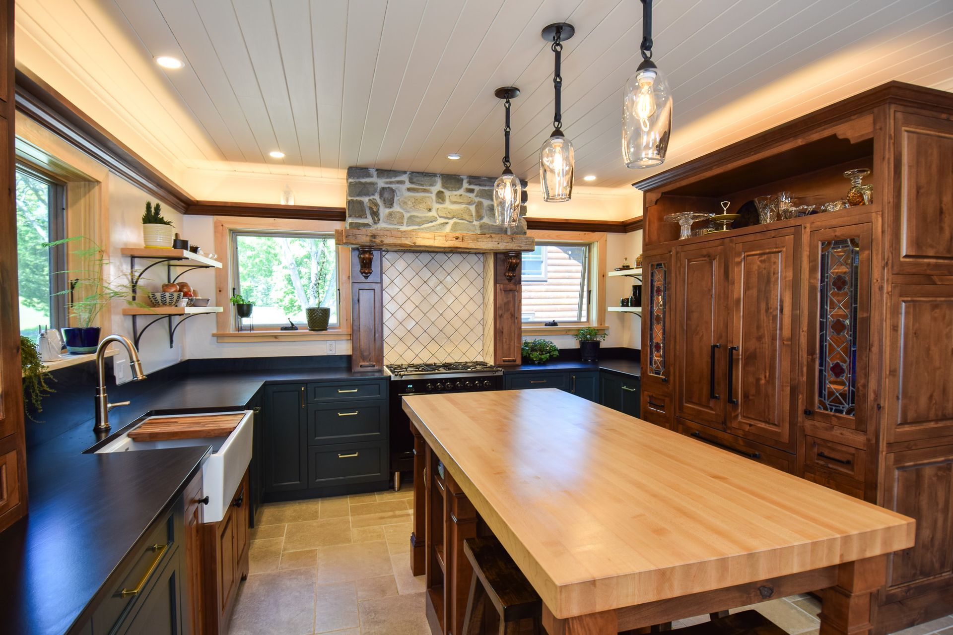 Modern kitchen with black cabinets, large wooden island, and ornate carved wood pantry cabinet