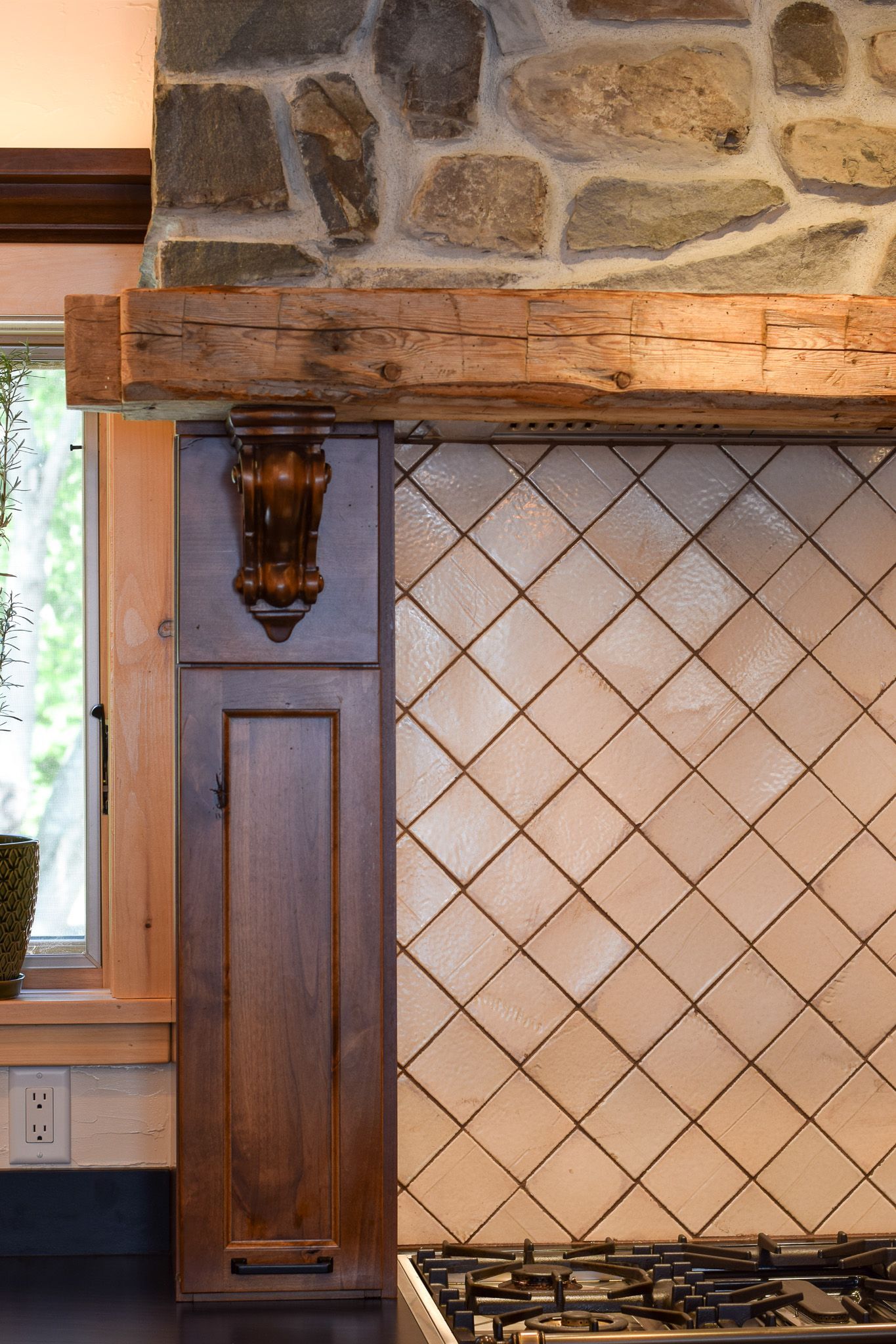 Kitchen backsplash with tan tile, dark wood trim, and stone wall above a stove