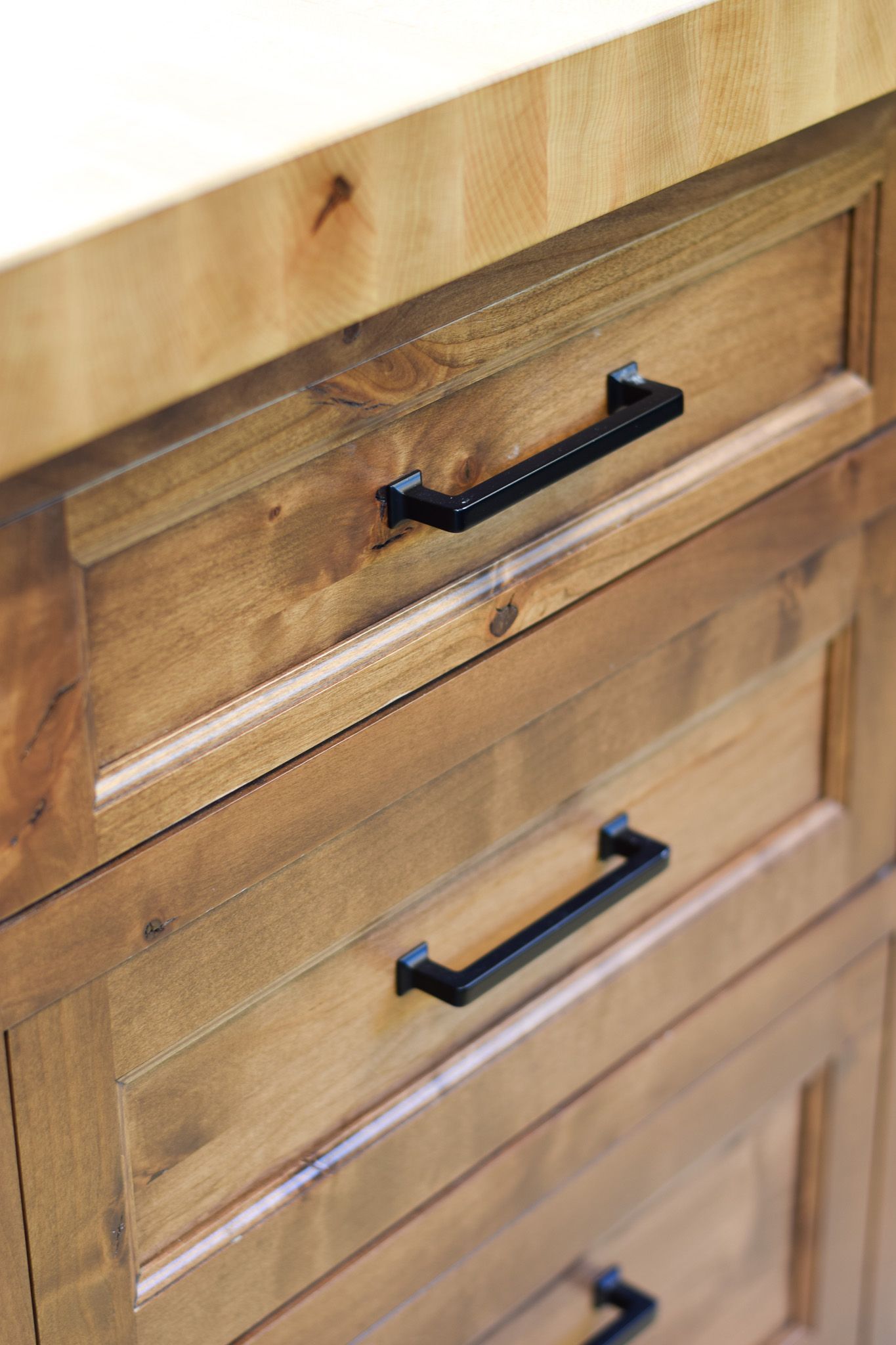 Wooden dresser drawers with black handles and a light wood finish