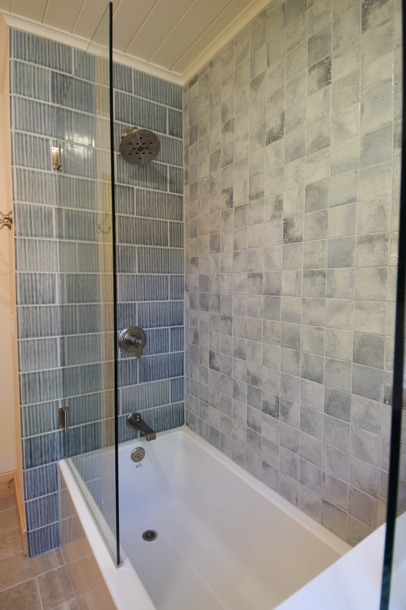 Modern tiled bathroom with a white bathtub and shower fixtures