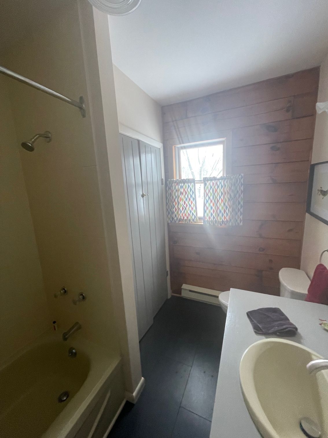 Small bathroom with a bathtub, toilet, sink, and a window letting in daylight.