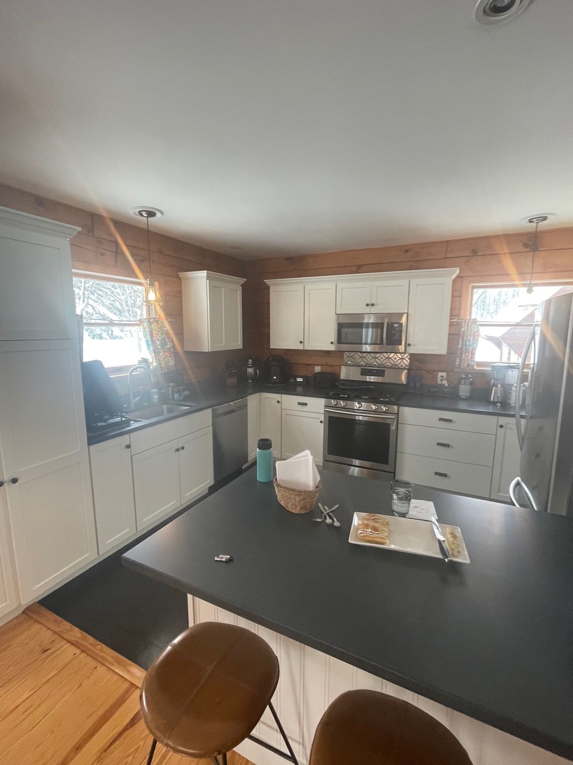 Modern kitchen with white cabinets, black countertops, stainless appliances, and a small island in the foreground