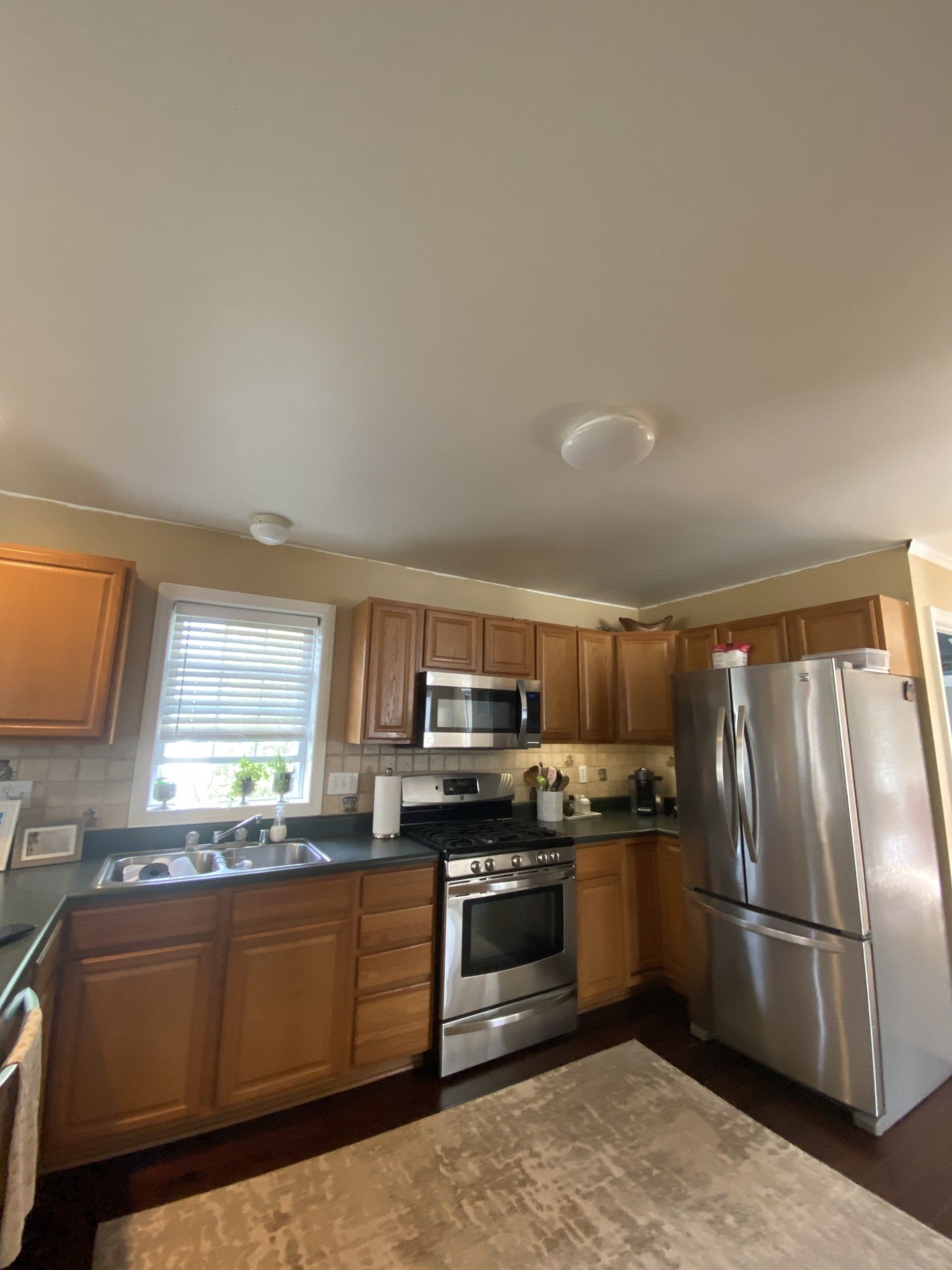 Small kitchen with wooden cabinets, stainless steel appliances, and a window over the sink.