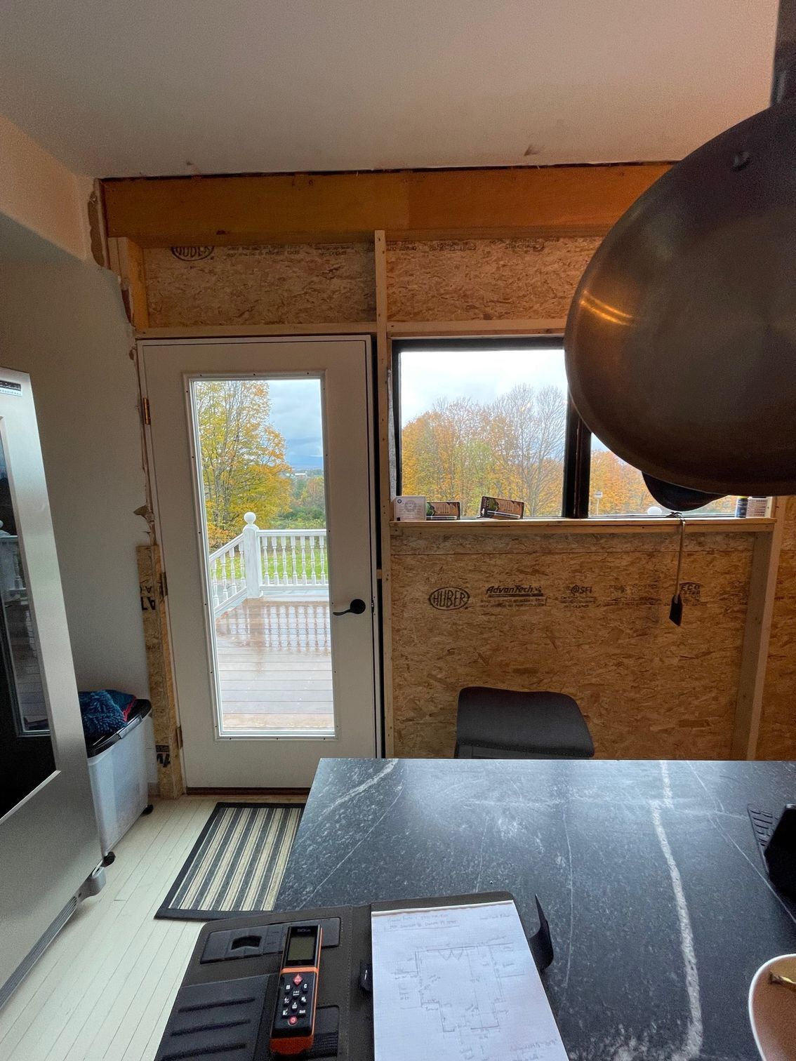 Interior view of a small room with a door, window, desk, and papers in the foreground
