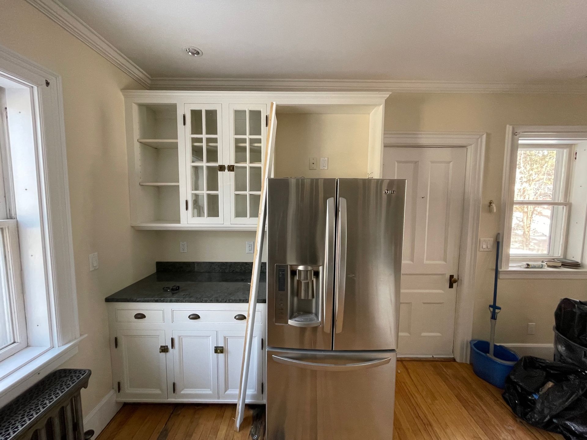 Bright kitchen with stainless steel refrigerator, white cabinets, and window light