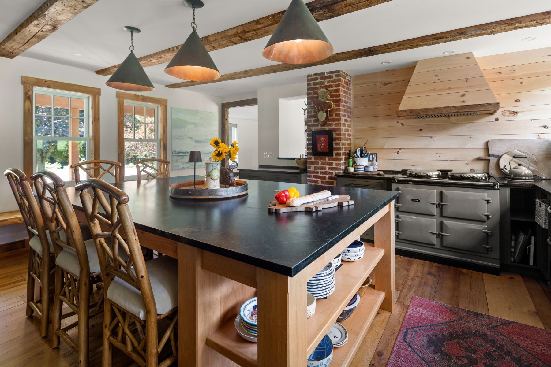 Modern kitchen with black island, pendant lights, bar stools, and stainless steel stove