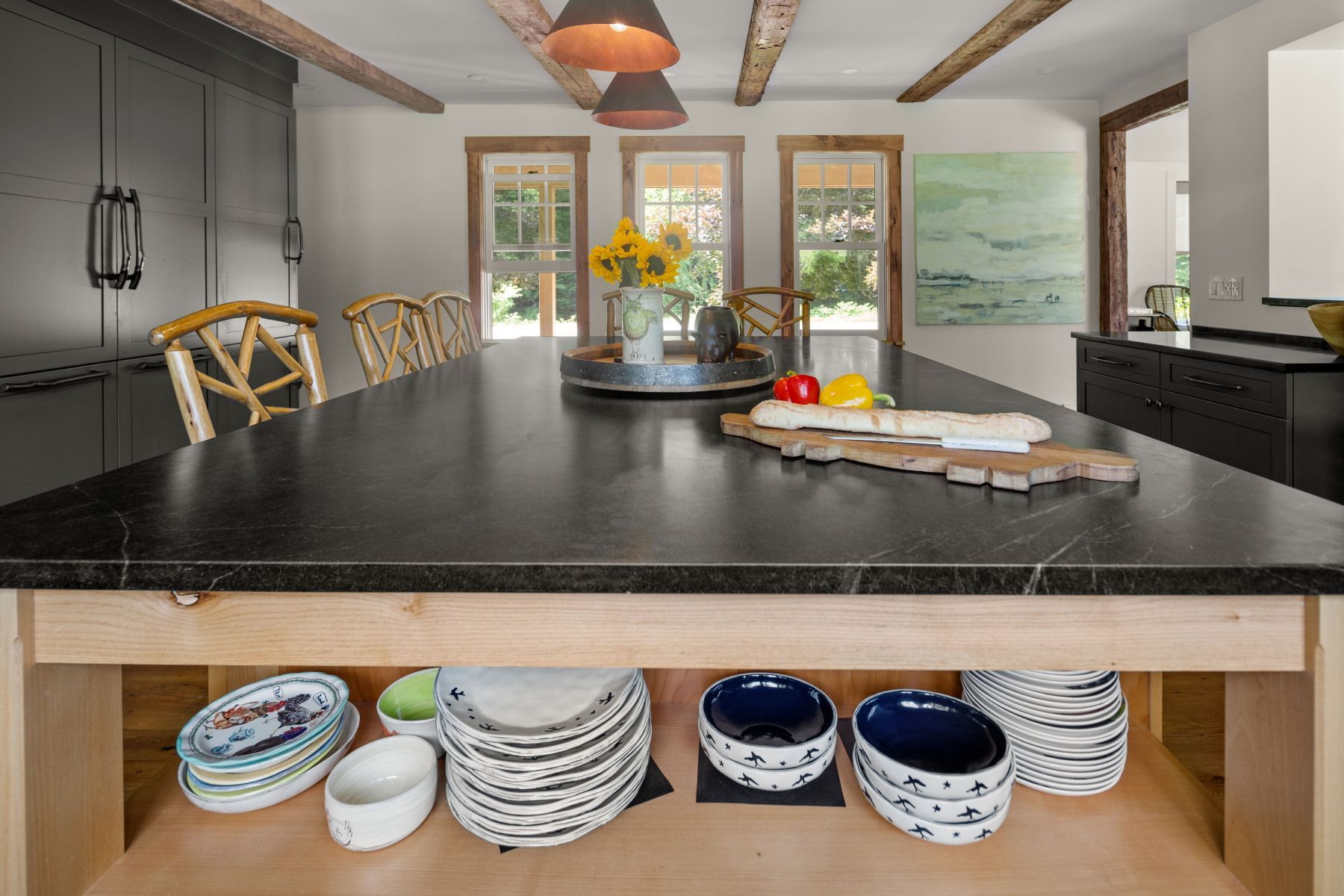 Modern kitchen with black island, fruit bowl, and open shelves of dishes
