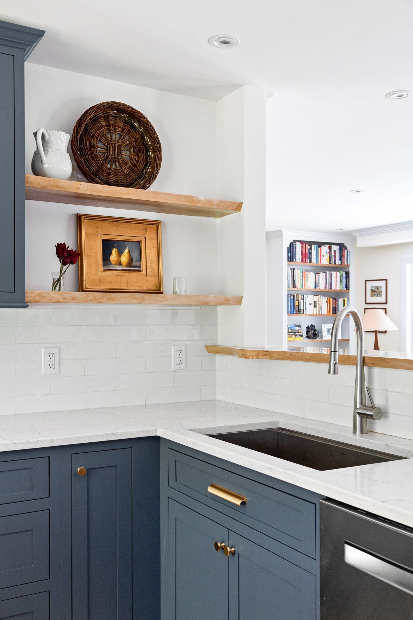Blue kitchen corner with open wood shelves, white tile backsplash, black sink, and built-in oven