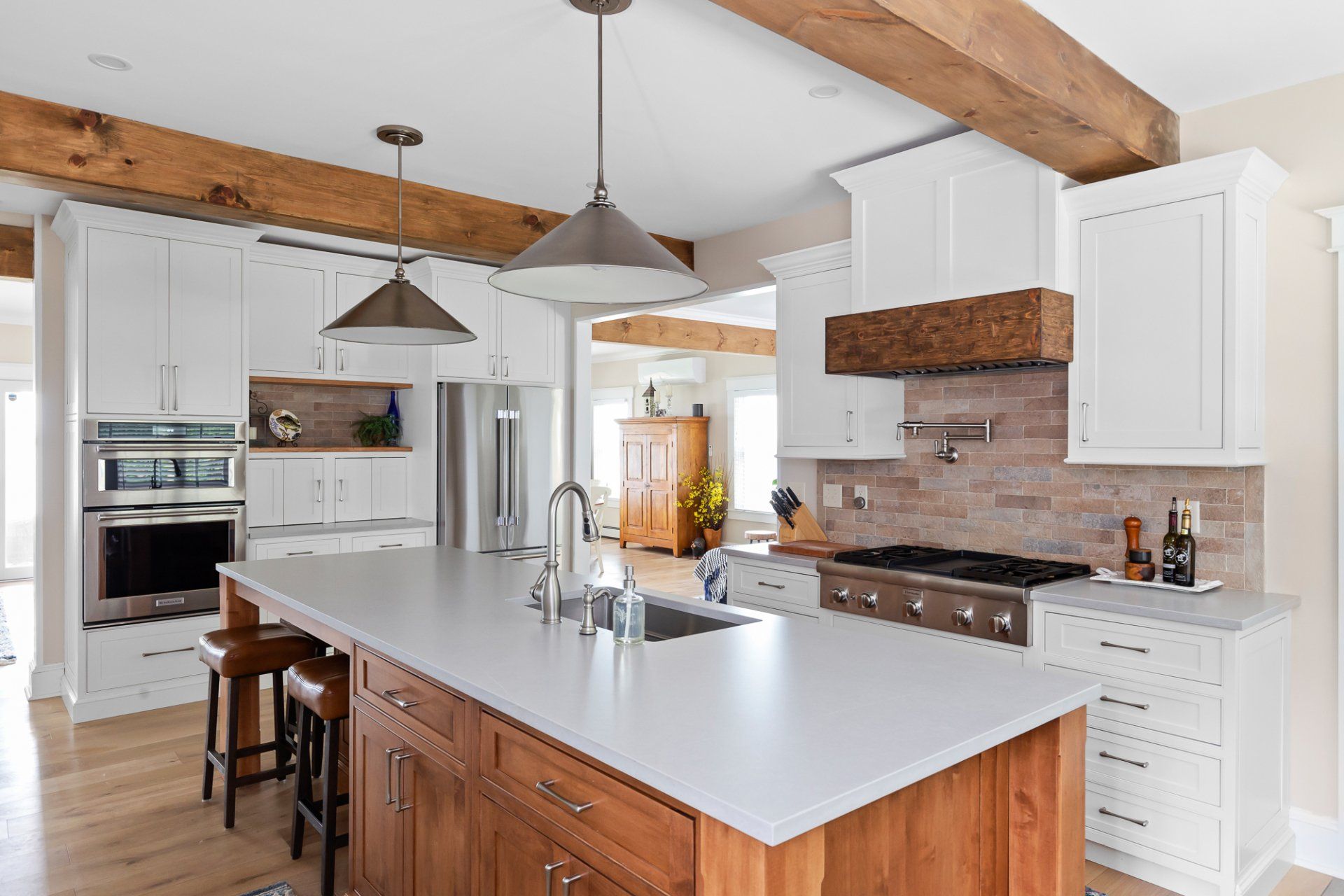 Bright modern kitchen with white cabinets, wood beams, and a large island with sink and stools
