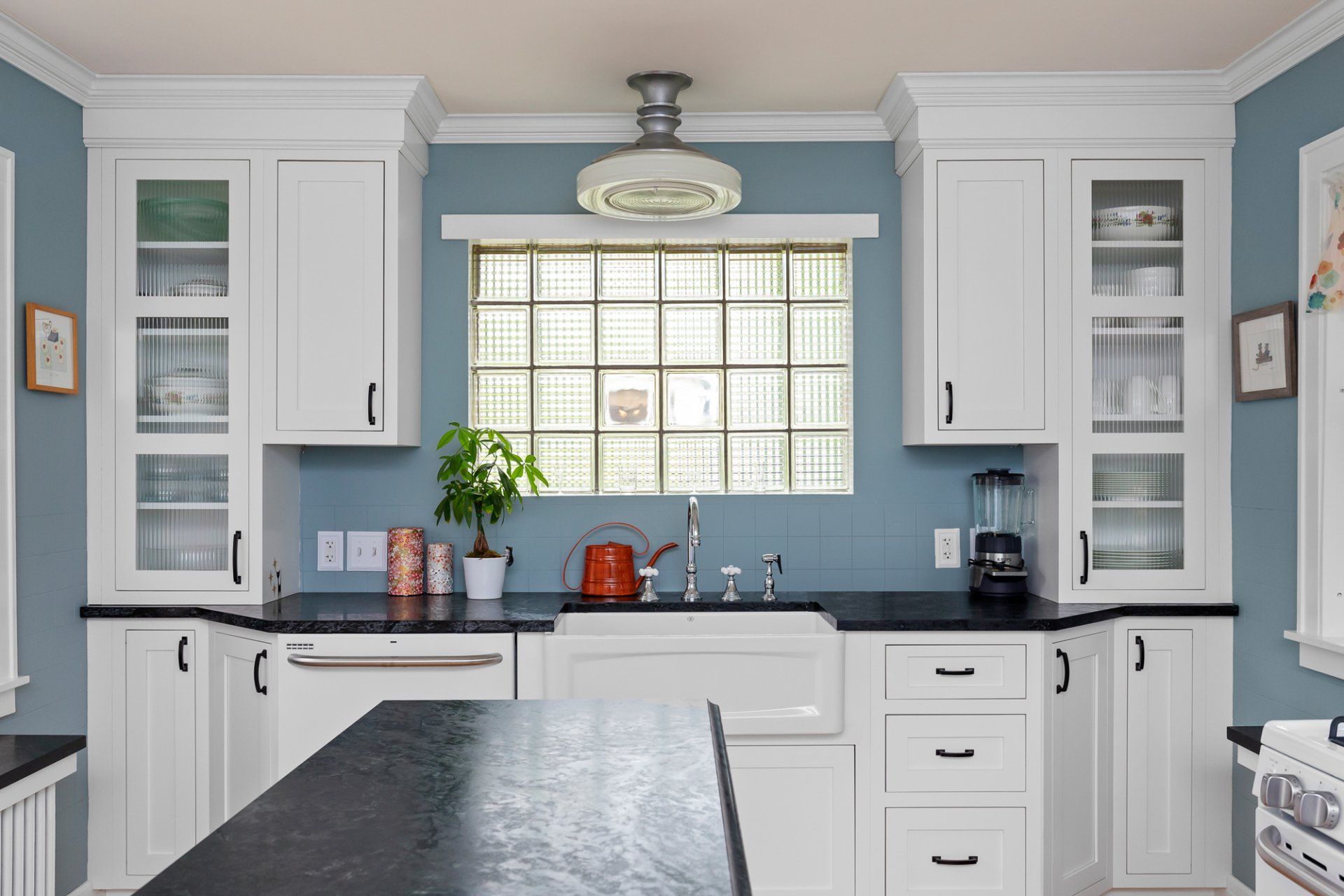 Bright kitchen with white cabinets, blue backsplash, and a large window over the sink