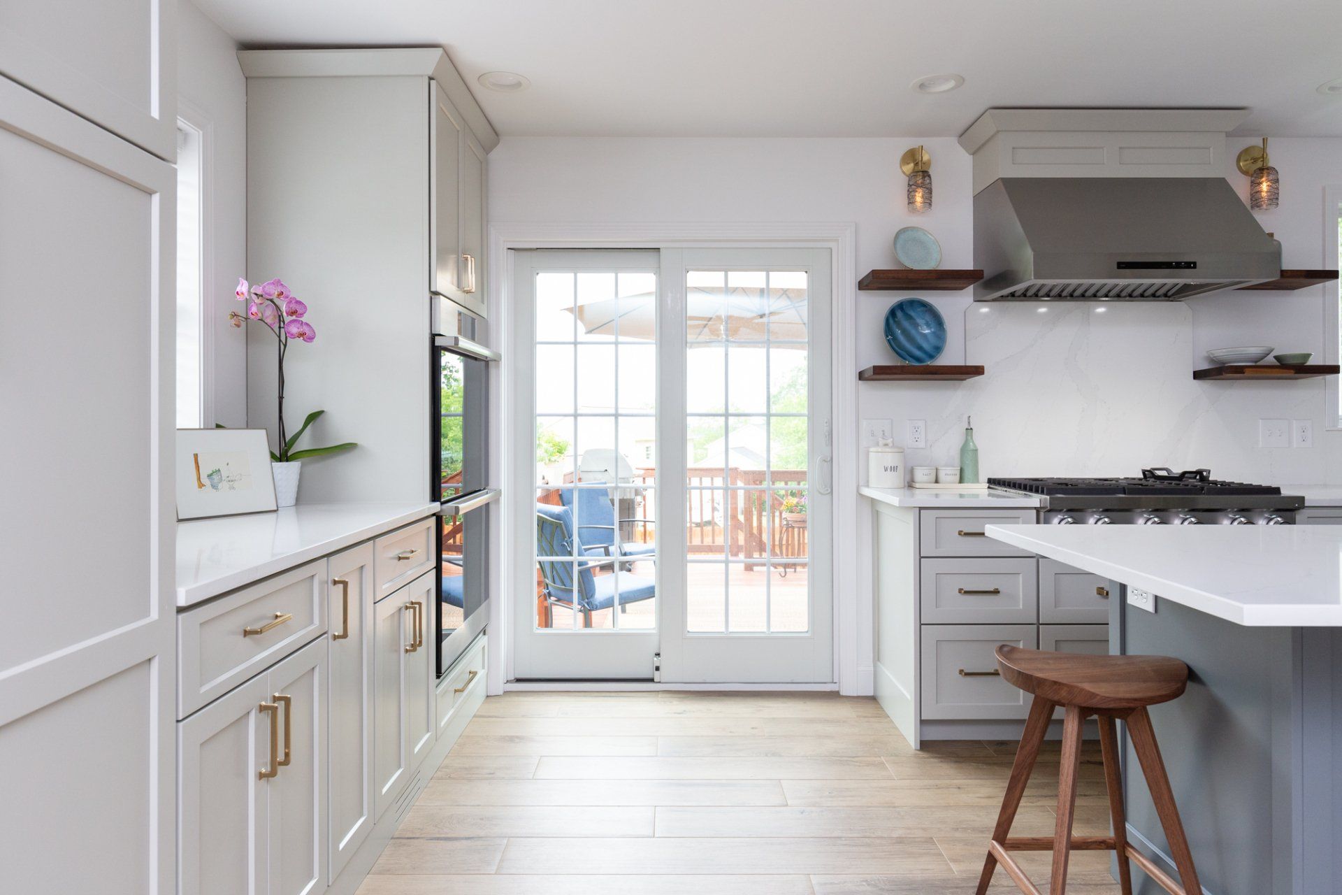 Bright white kitchen with gray cabinets, open shelves, and French doors leading outside